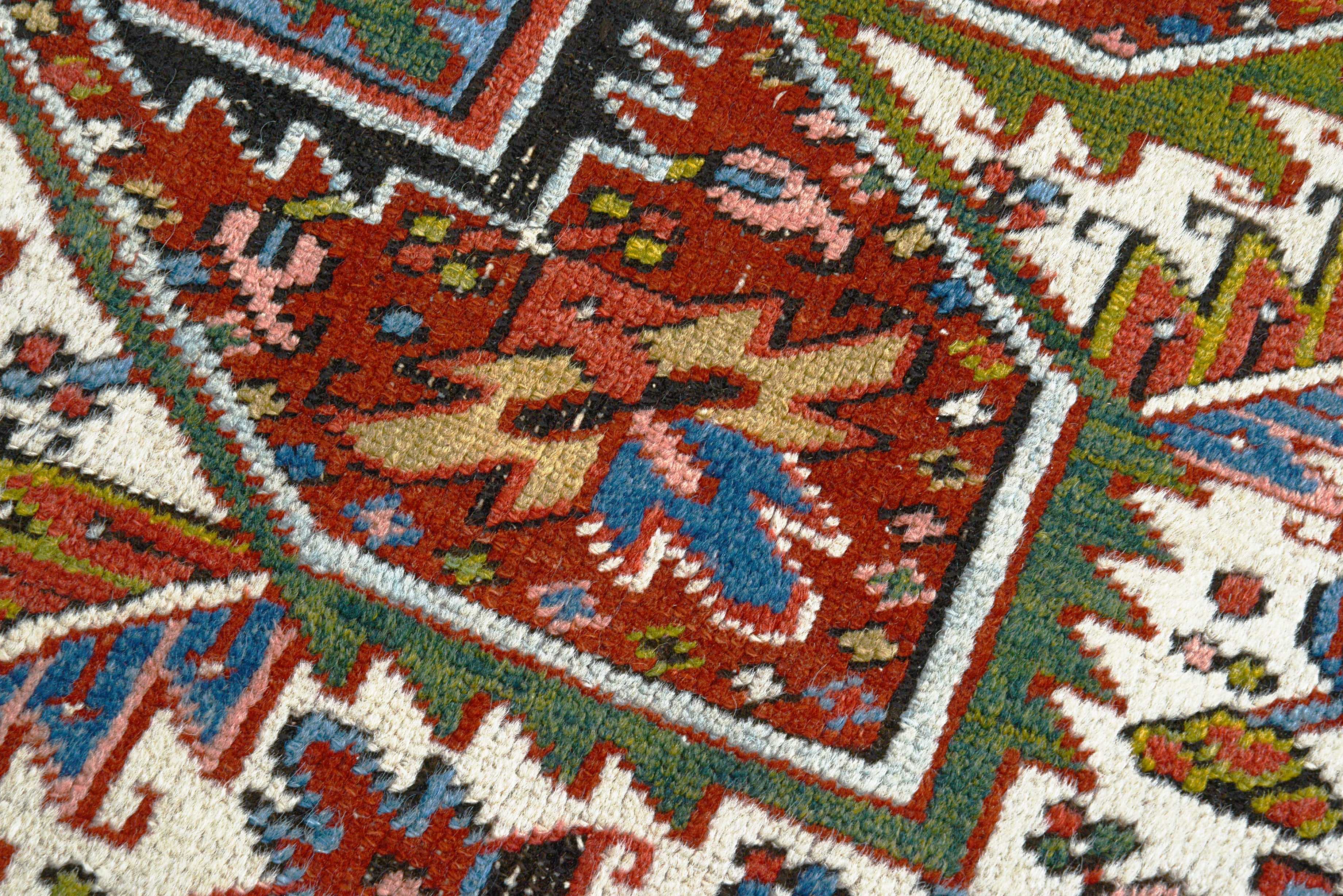 Close-up details of antique Persian Heriz carpet showing wool texture, motifs, and aged patina