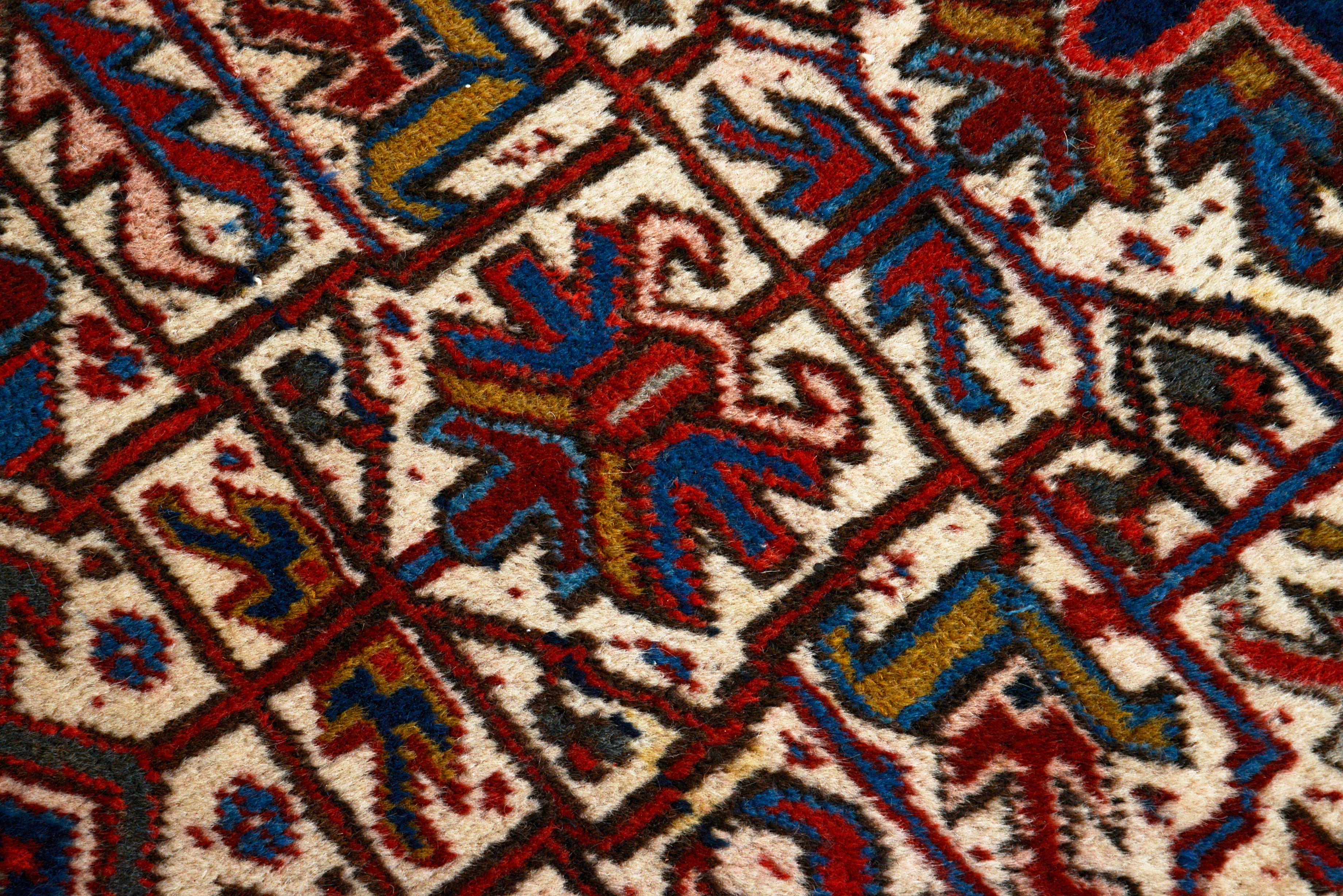 Close-up details of vintage Heriz carpet showing wool texture, motifs, and natural patina