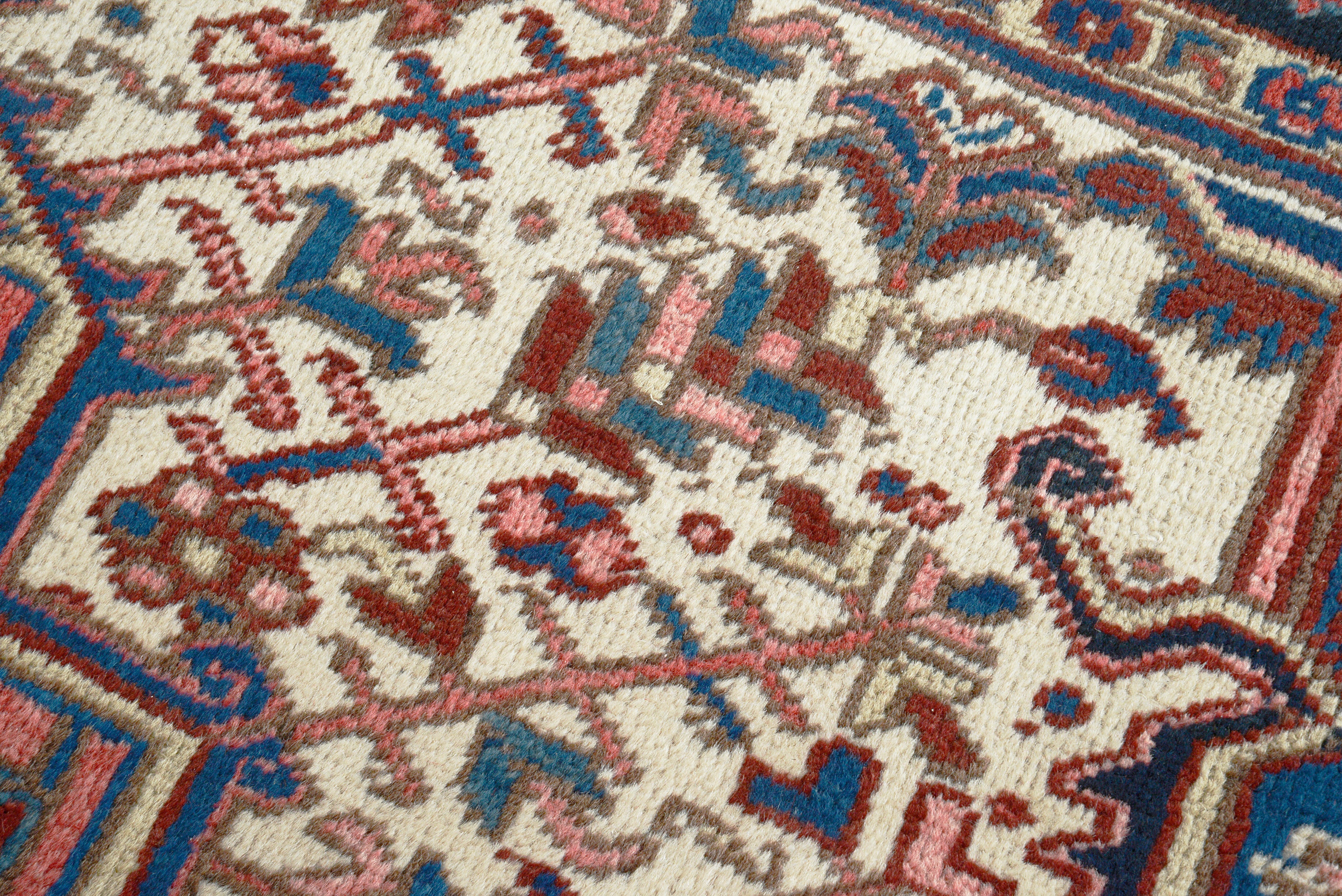 Close-up details of vintage Heriz carpet showing wool texture, motifs, and natural patina