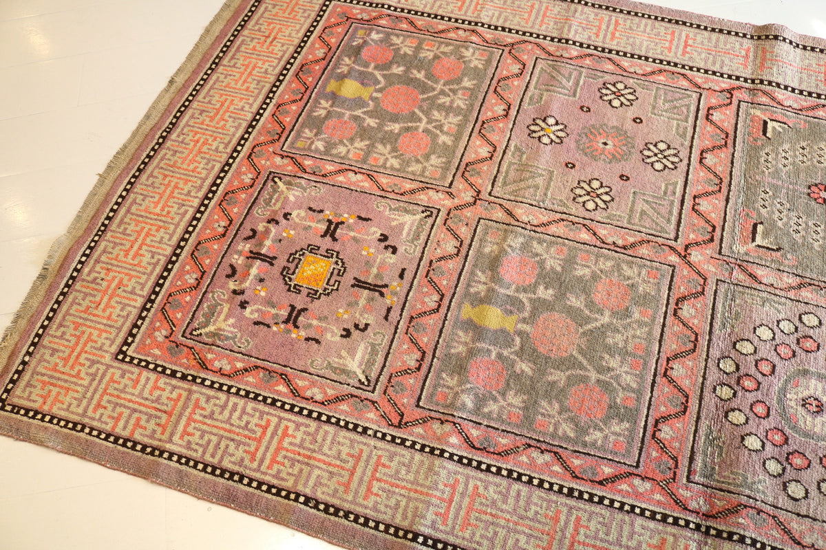 Angled view showing muted floral motifs across the Qotan rug field