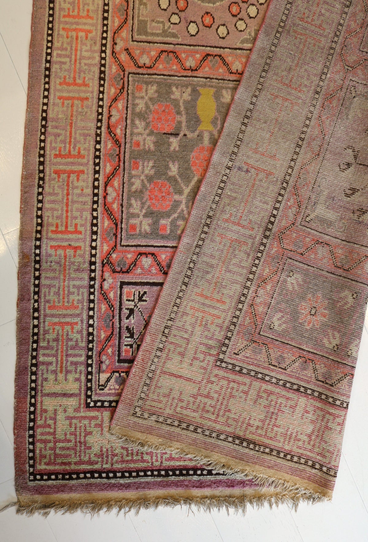 Folded Qotan rug showing patterned surface, borders and reverse sidE