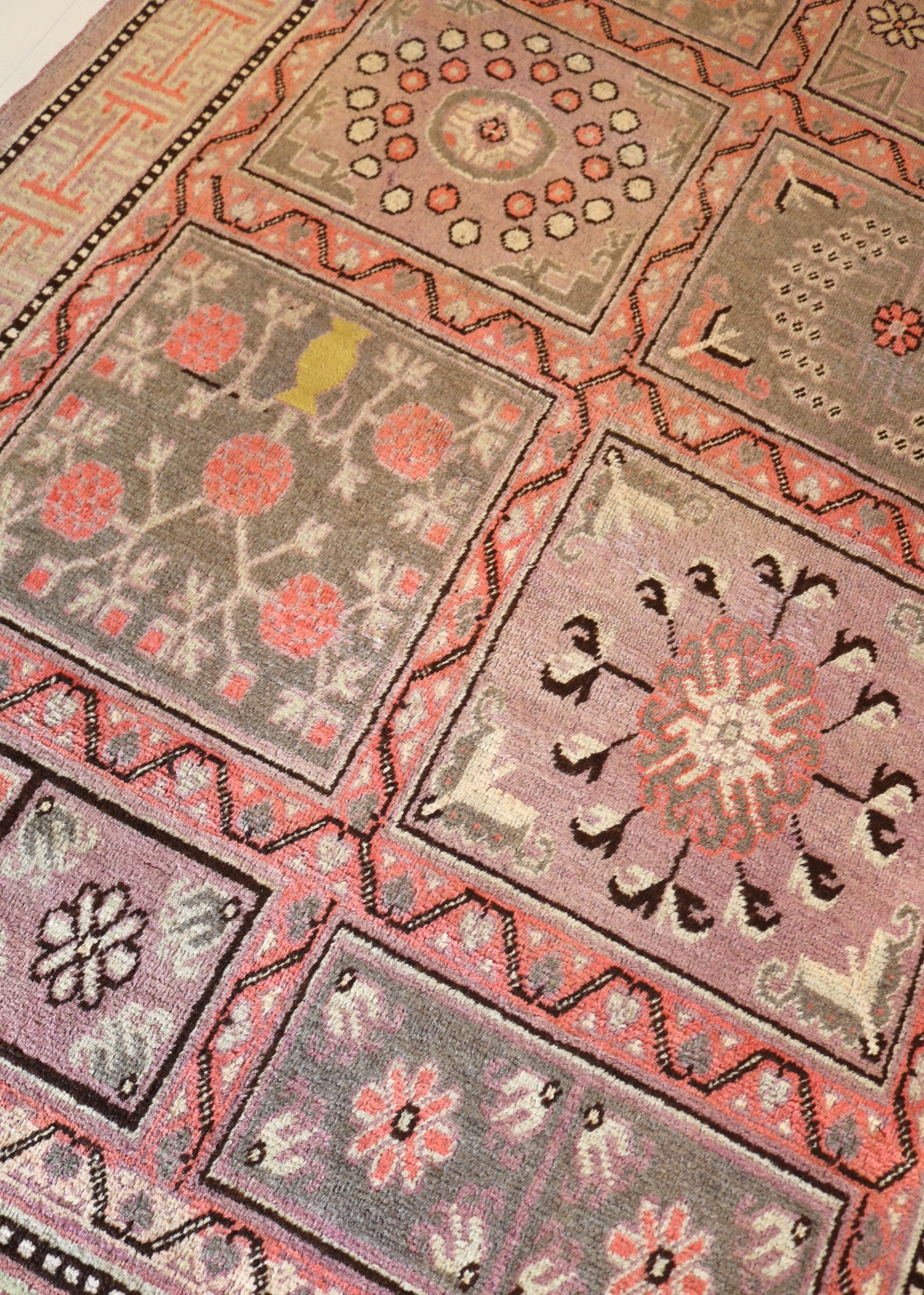 Close-up of Qotan rug with geometric panels and floral motifs