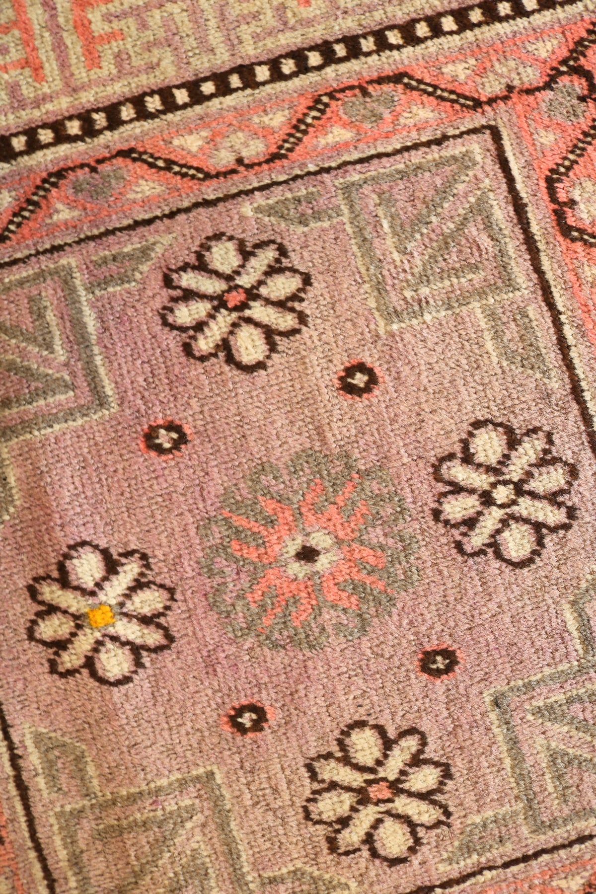 Detailed Qotan rug section featuring small floral motifs on a pink field