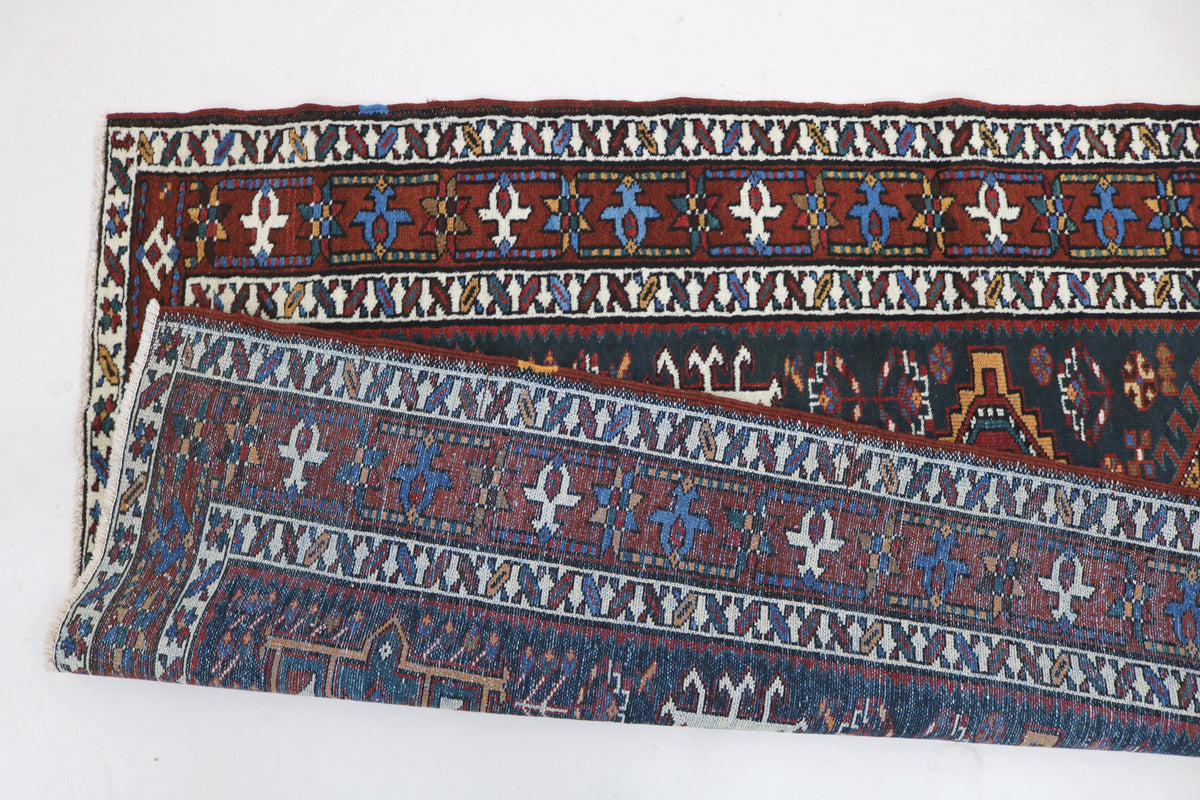 Folded Persian Heriz runner showing detailed geometric borders and woven reverse side