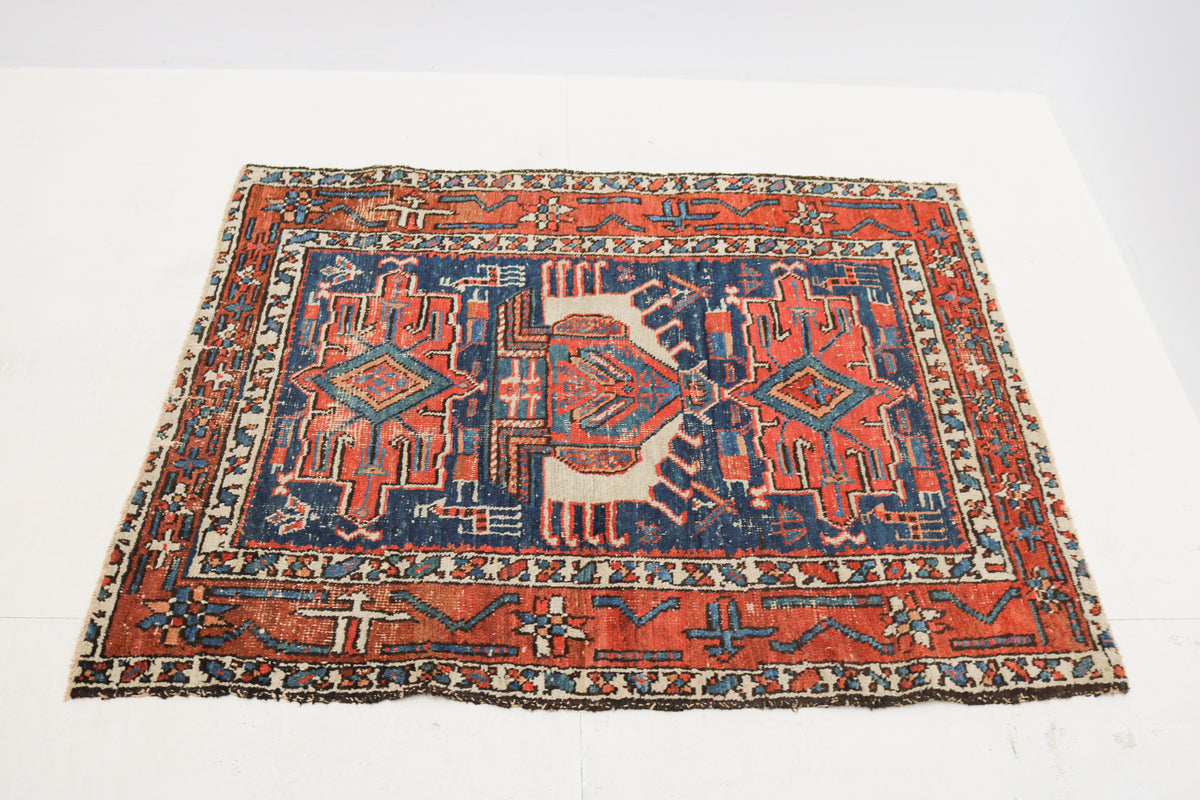Antique Persian rug shown from above with a traditional geometric design and decorative borders