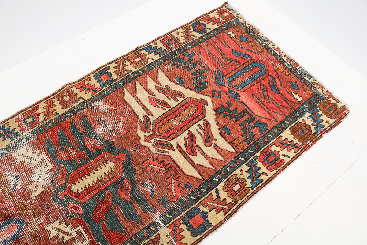 Close-up of an antique Persian runner rug showing traditional geometric motifs and detailed border