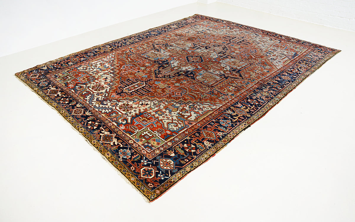 Angled view of Persian Heriz carpet featuring geometric motifs and richly patterned borders