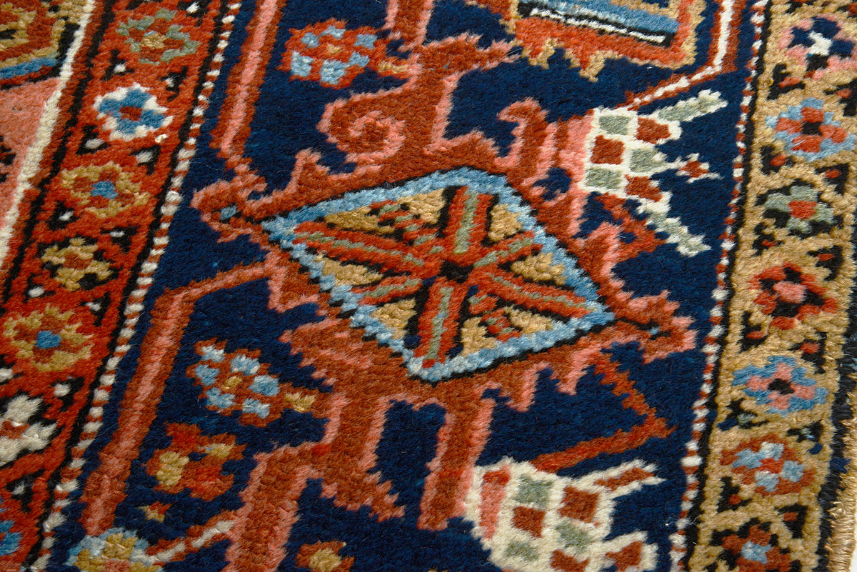 Detailed Heriz carpet corner featuring geometric motifs and contrasting indigo border