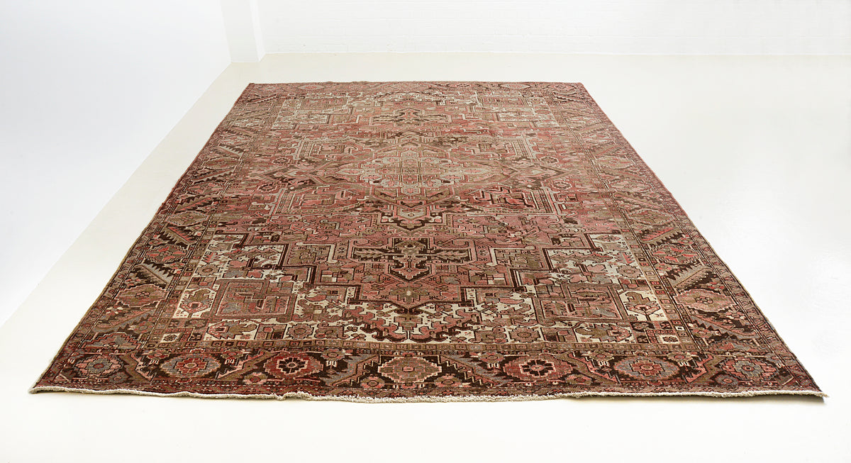 Full view of antique Heriz carpet with geometric composition and softly aged earthy colours