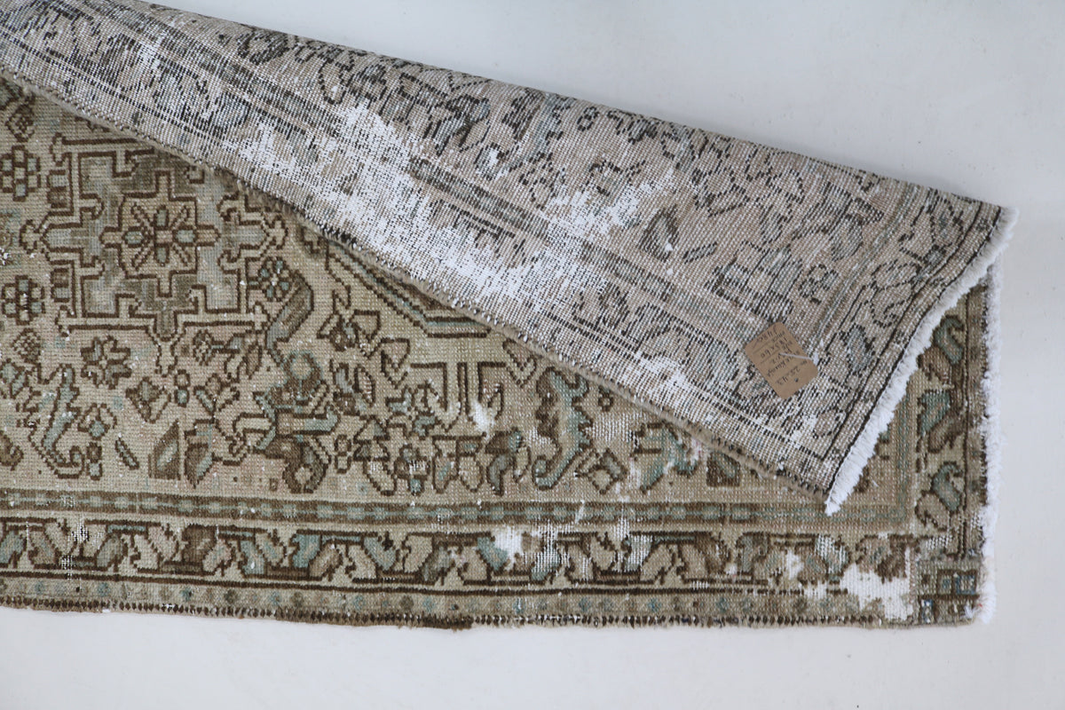 Folded corner of antique Heriz runner showing patterned reverse and woven texture