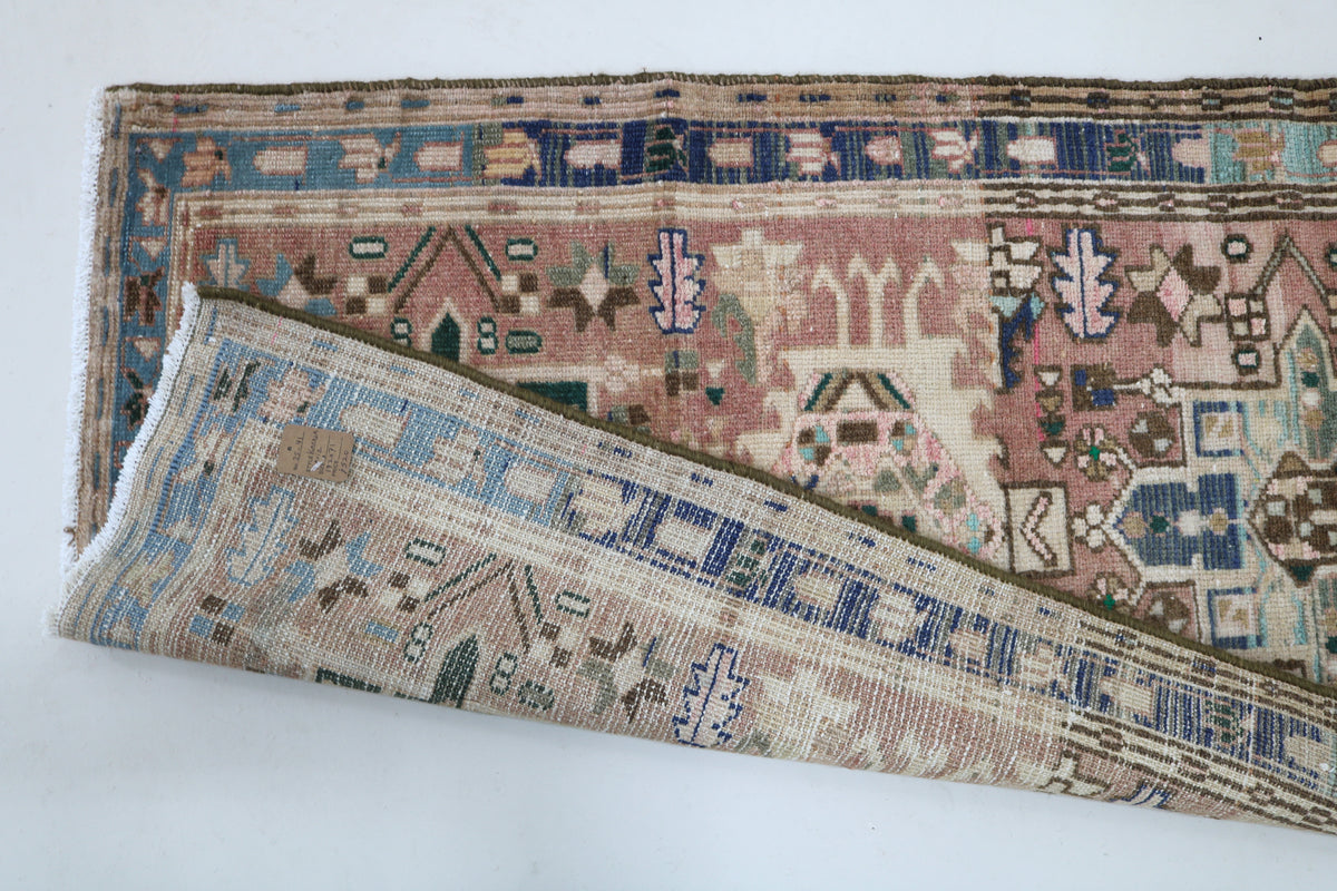 Detailed Heriz runner surface with muted pink field and geometric designs