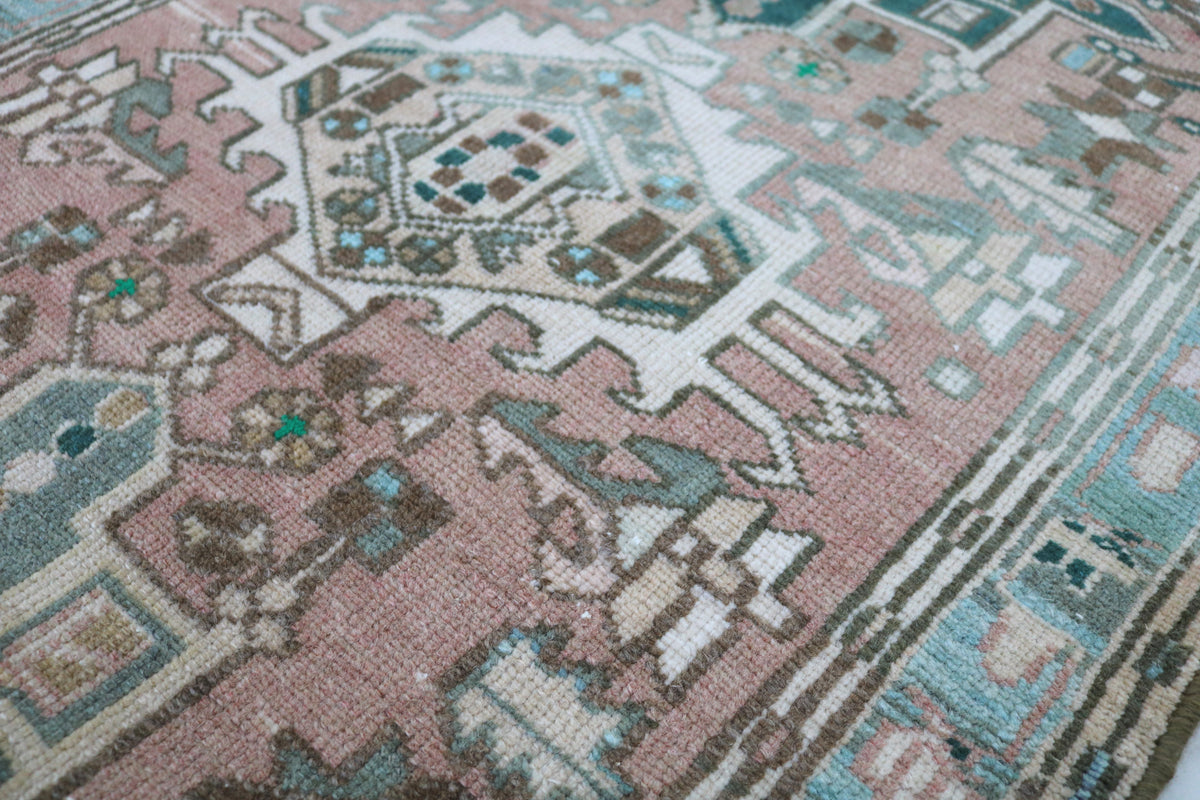 Detailed Persian Heriz pattern with layered geometric shapes in pink, blue and beige