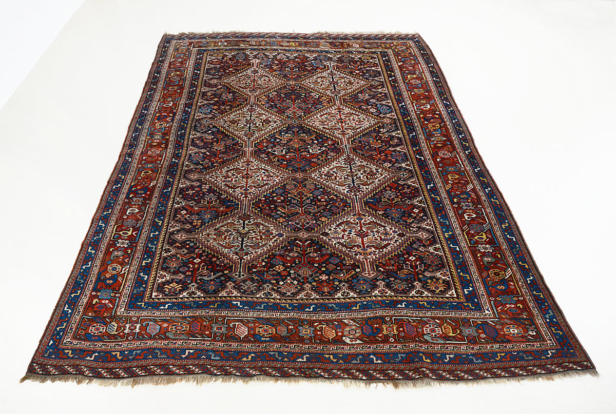 Full view of antique Qashqai carpet with diamond lattice design in red, blue and ivory