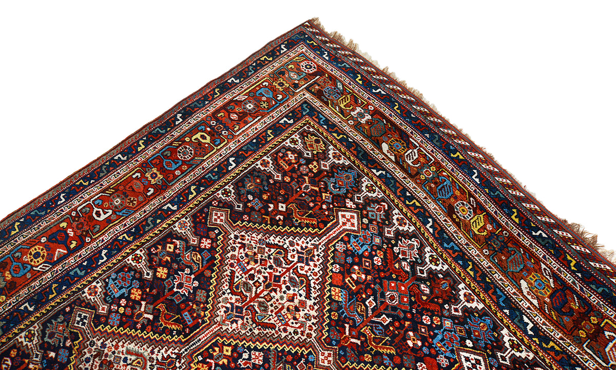 Corner view of Persian Qashqai carpet with geometric motifs in red, blue and ivory
