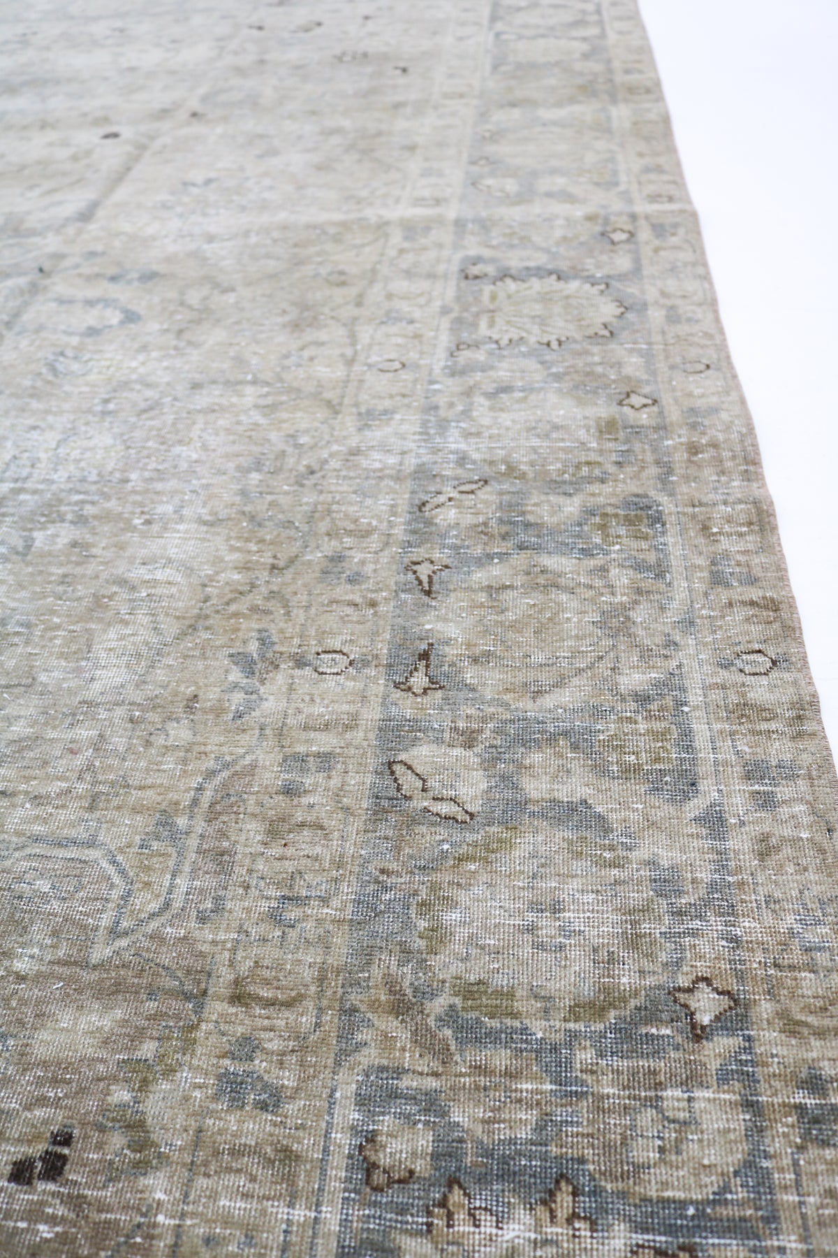 Side view of antique Persian Tabriz carpet showing floral field and layered borders