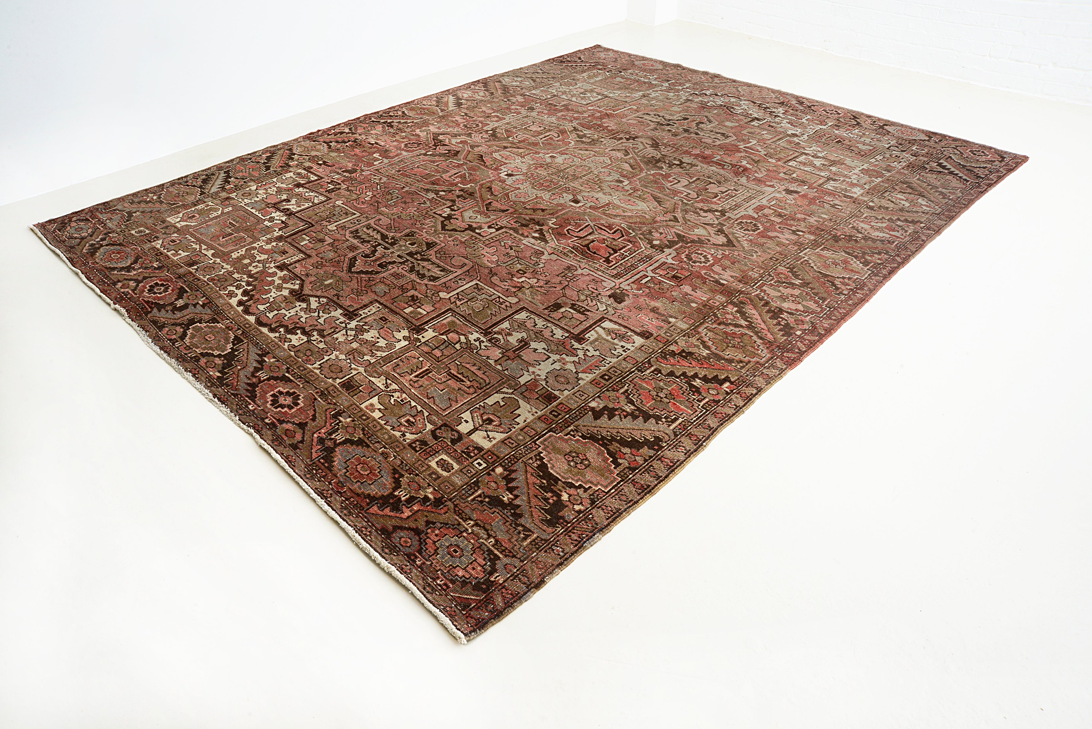 Angled view of antique Persian Heriz carpet showing overall pattern