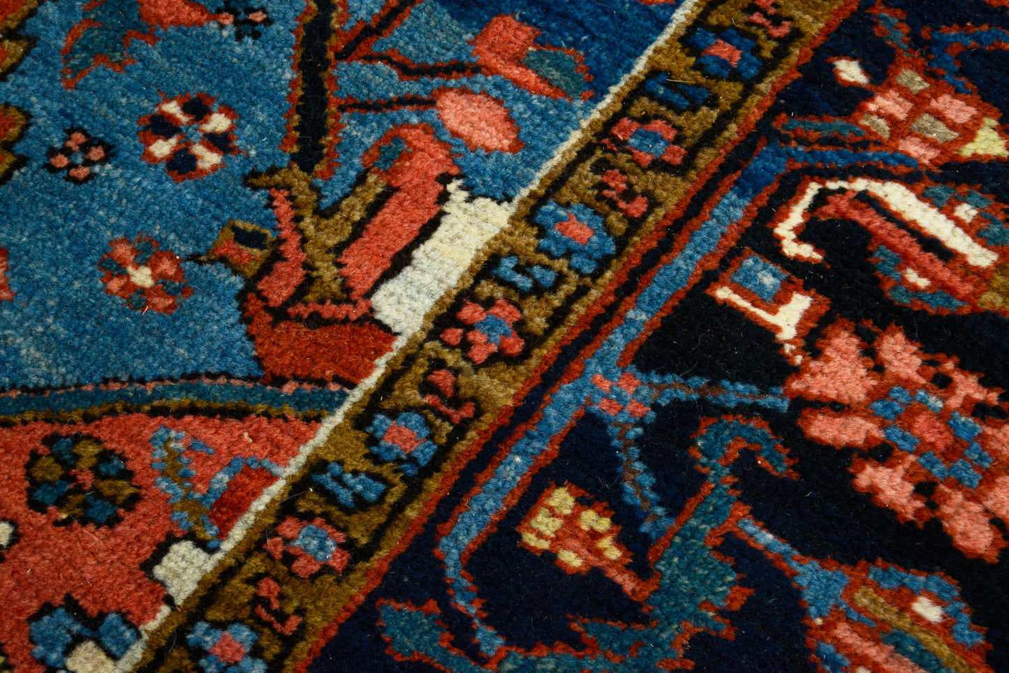 Close-up of hand-knotted wool texture on antique Persian Heriz carpet