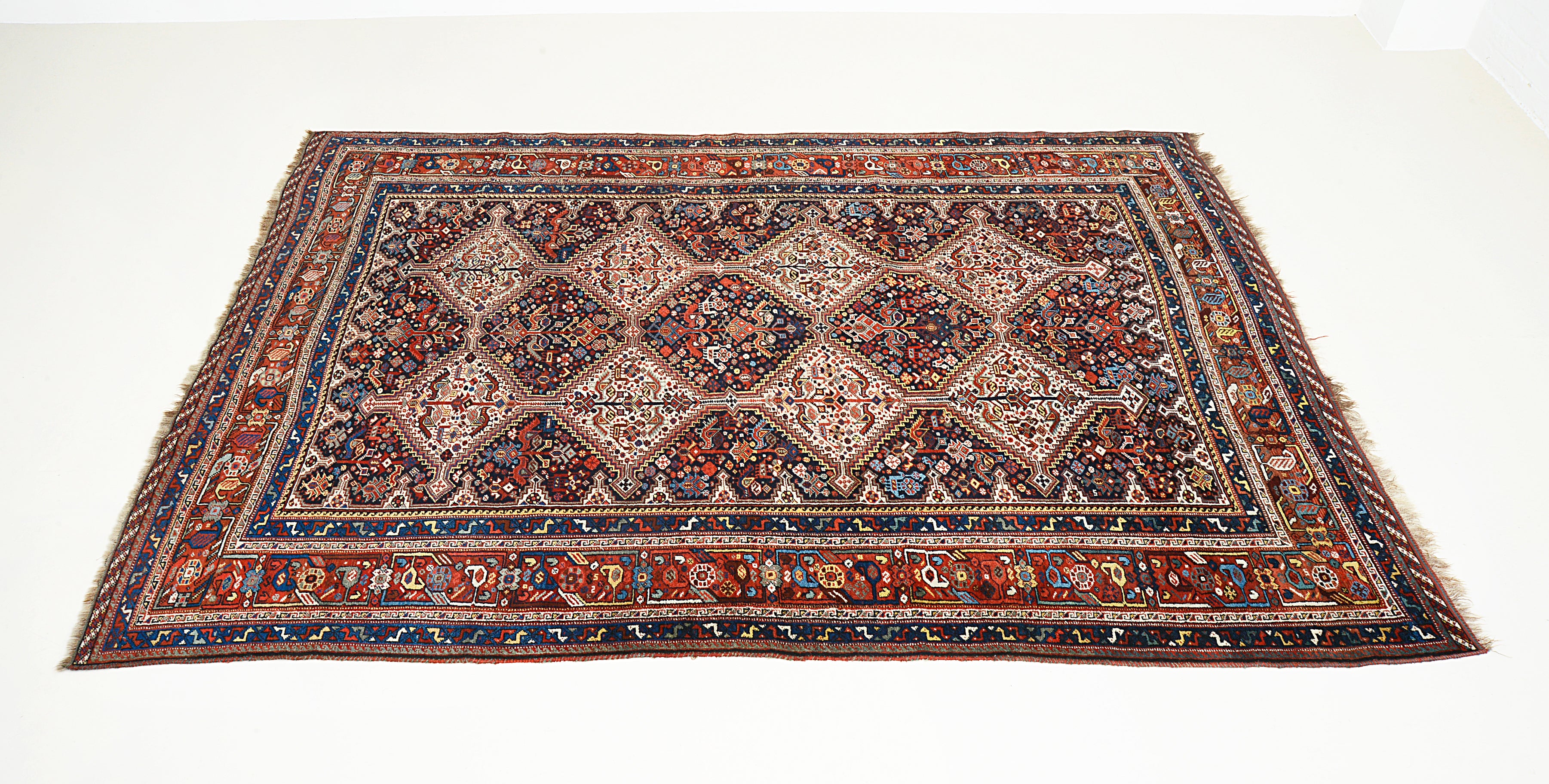 Angled view of an antique Persian Qashqai carpet highlighting overall composition and proportions