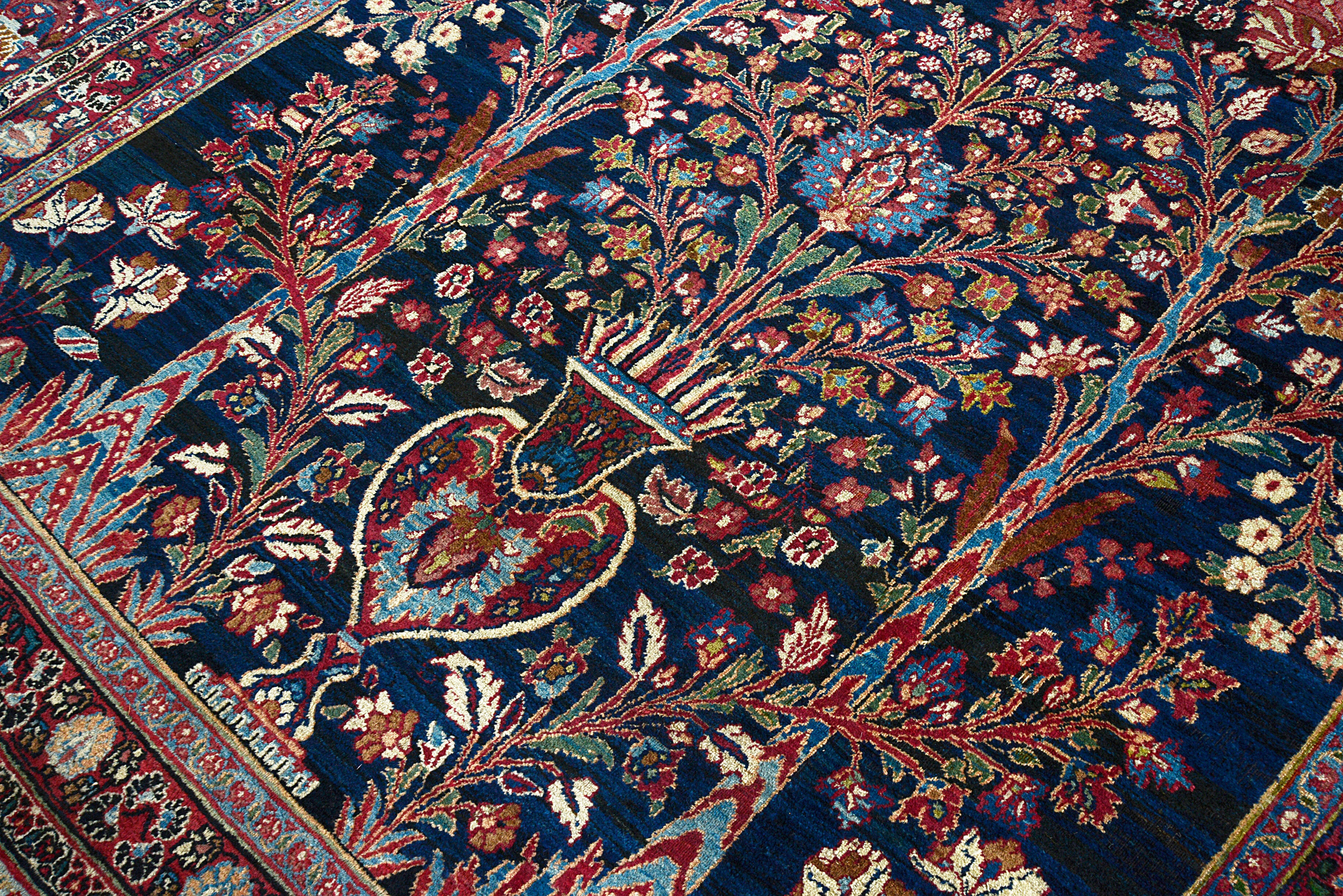 Close-up of finely detailed floral drawing on an antique Persian Mashhad carpet