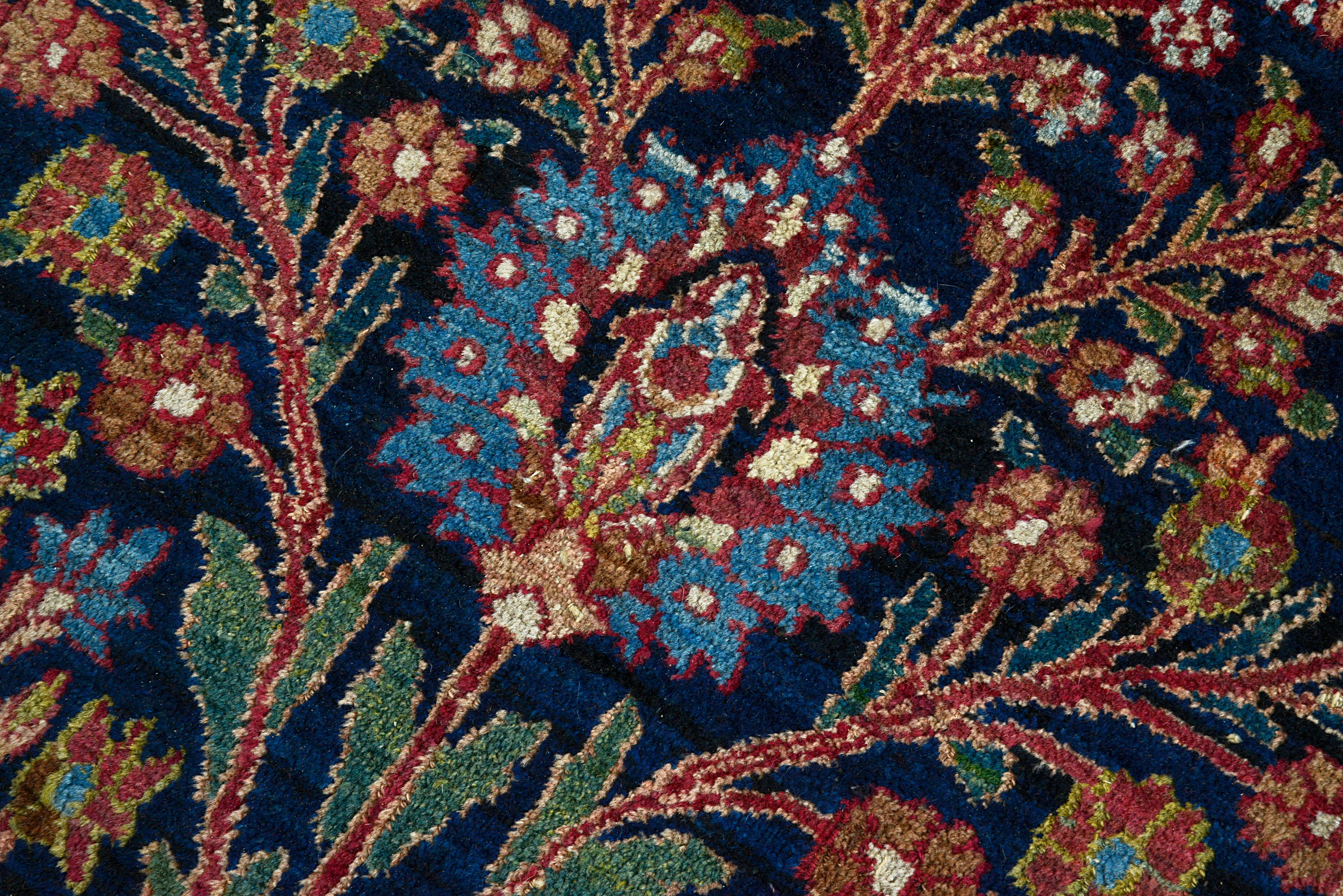 Hand-knotted wool texture of an antique Persian Mashhad carpet