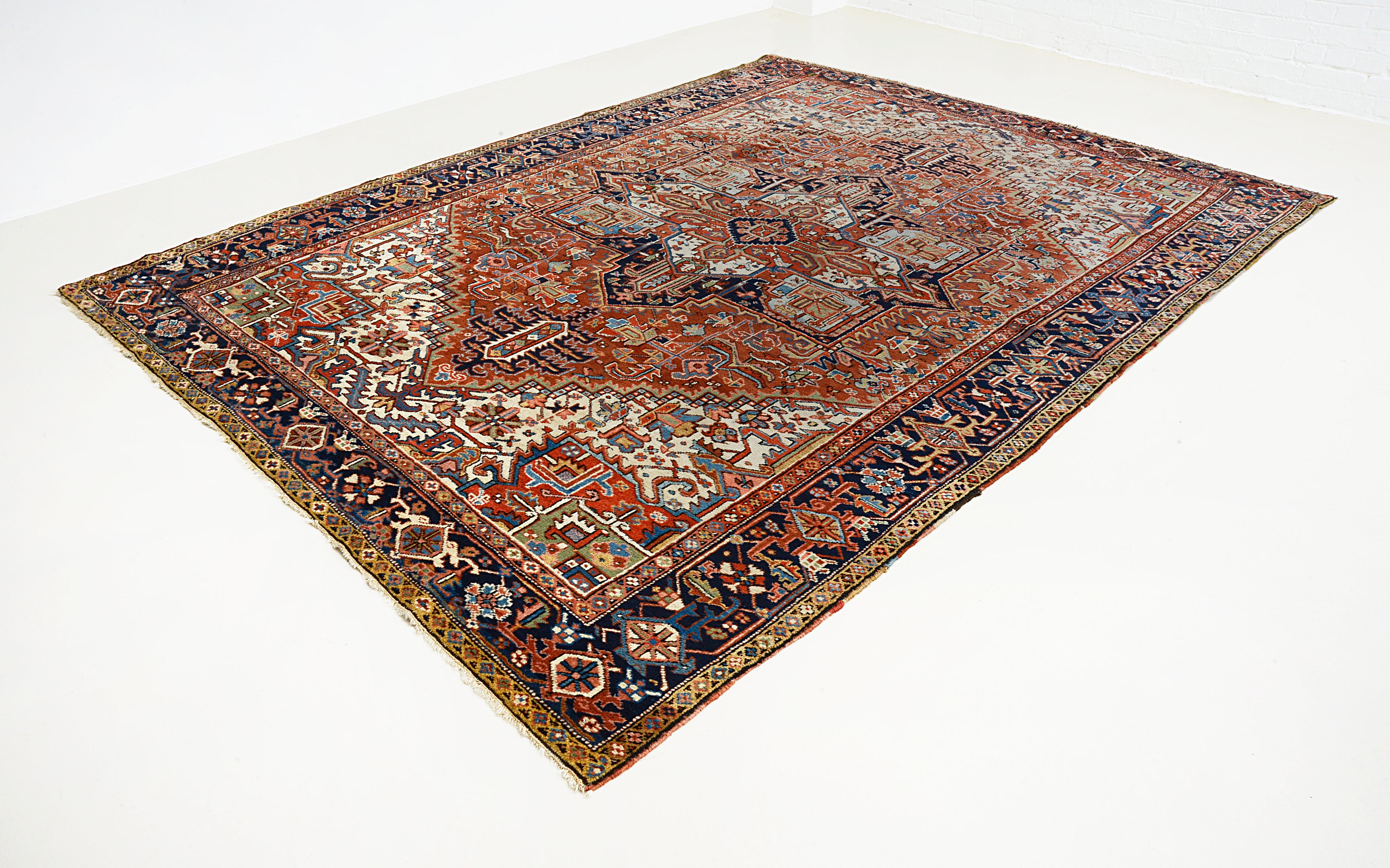 Angled view of an antique Persian Heriz carpet highlighting its large scale and overall composition
