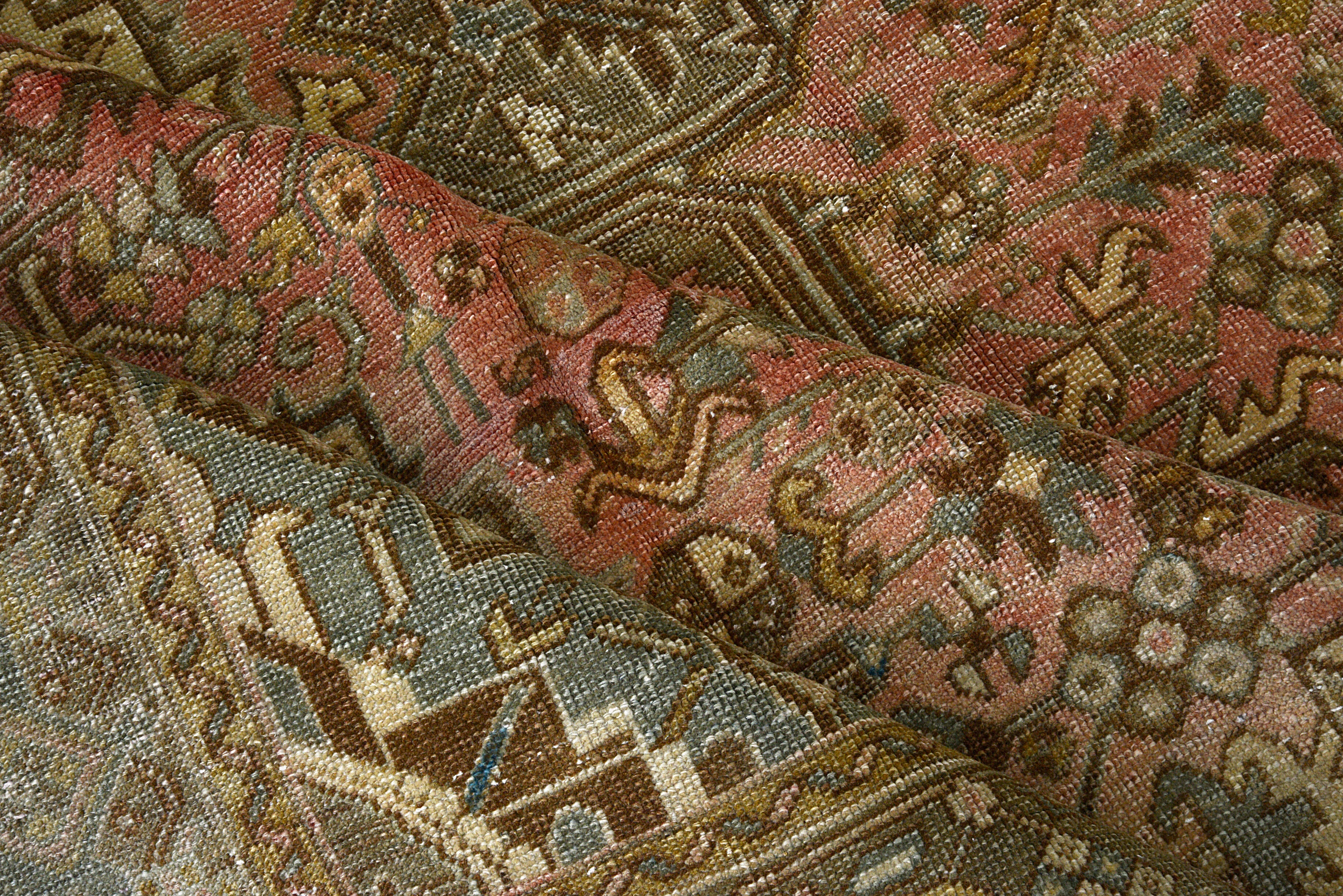 Detail of vintage Persian Heriz carpet showing wool texture, geometric motifs and natural colour variation from age and use