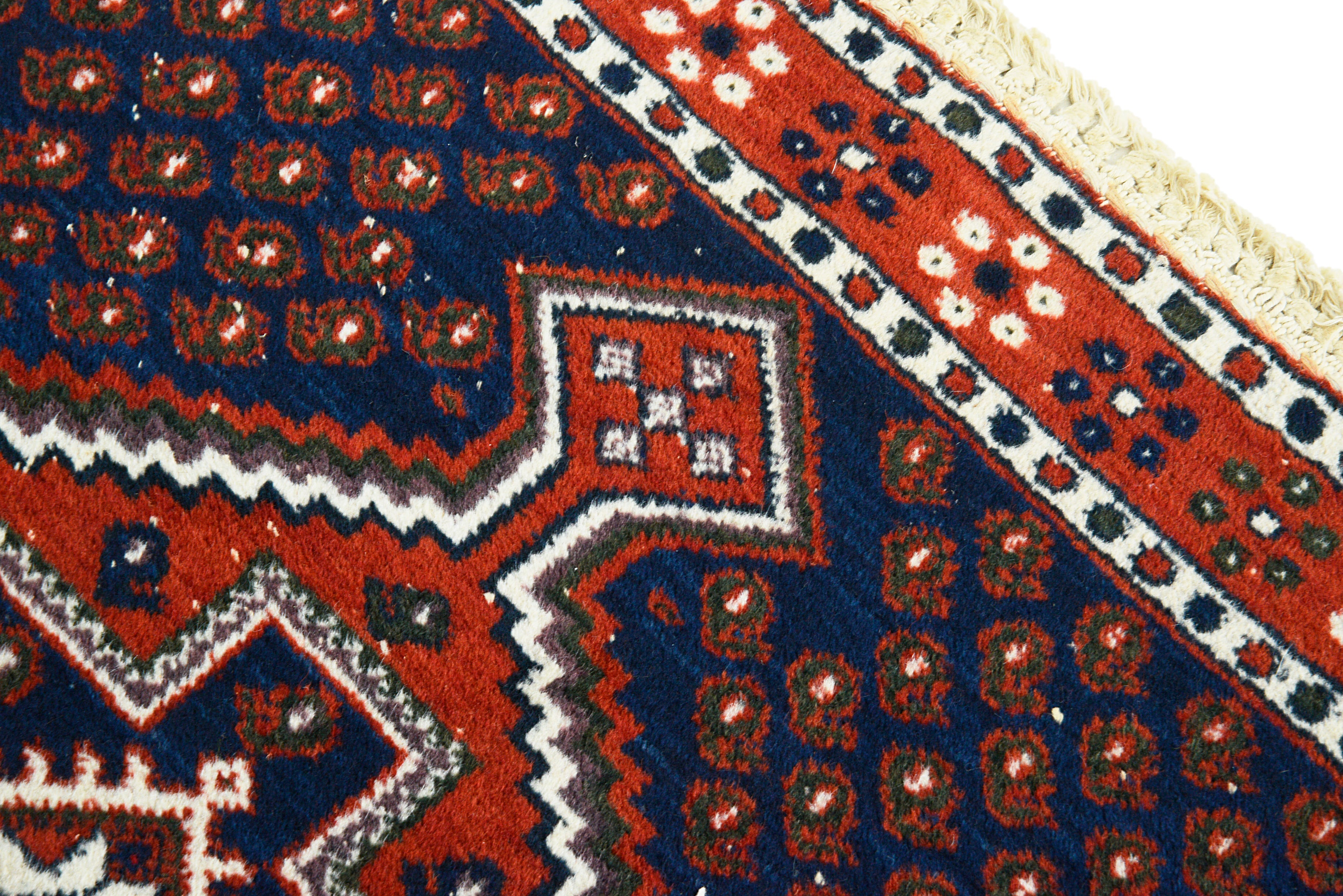 Close-up of red and blue geometric patterns on an antique Persian Afshar rug