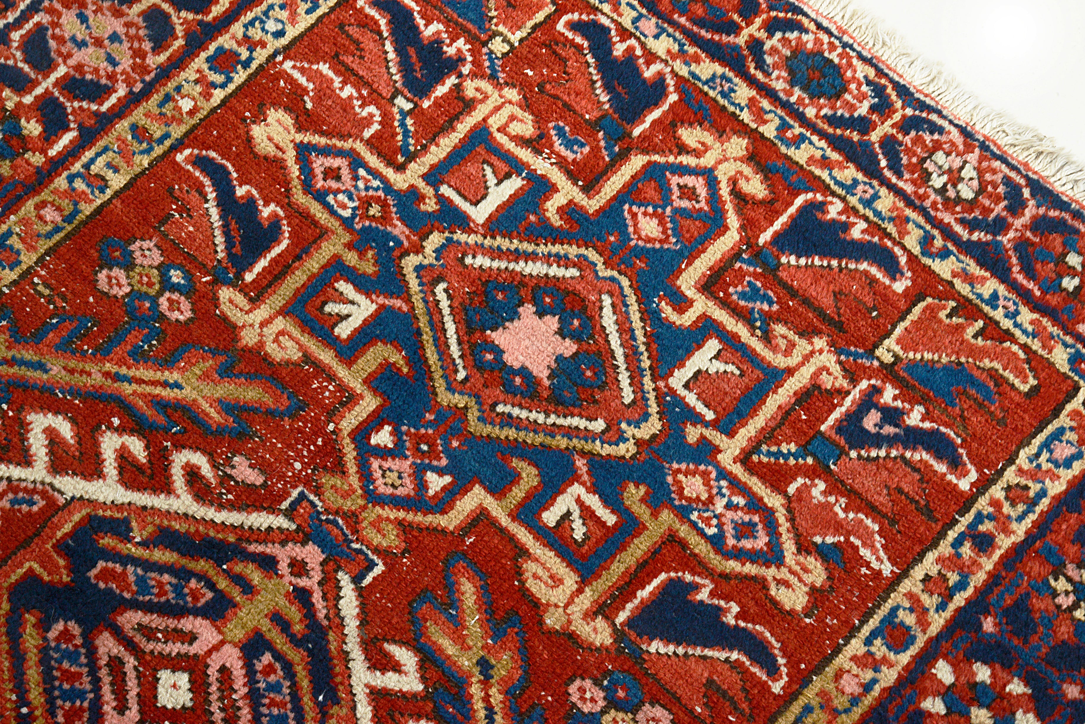 Close-up of a patterned Antique Persian Heriz rug with red, blue, and beige colors.
