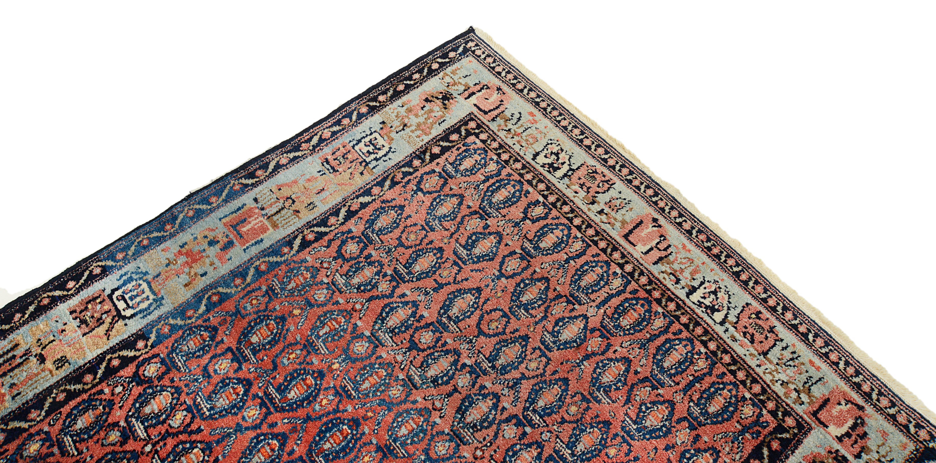 Corner of an Antique Senneh rug with intricate patterns on a white background