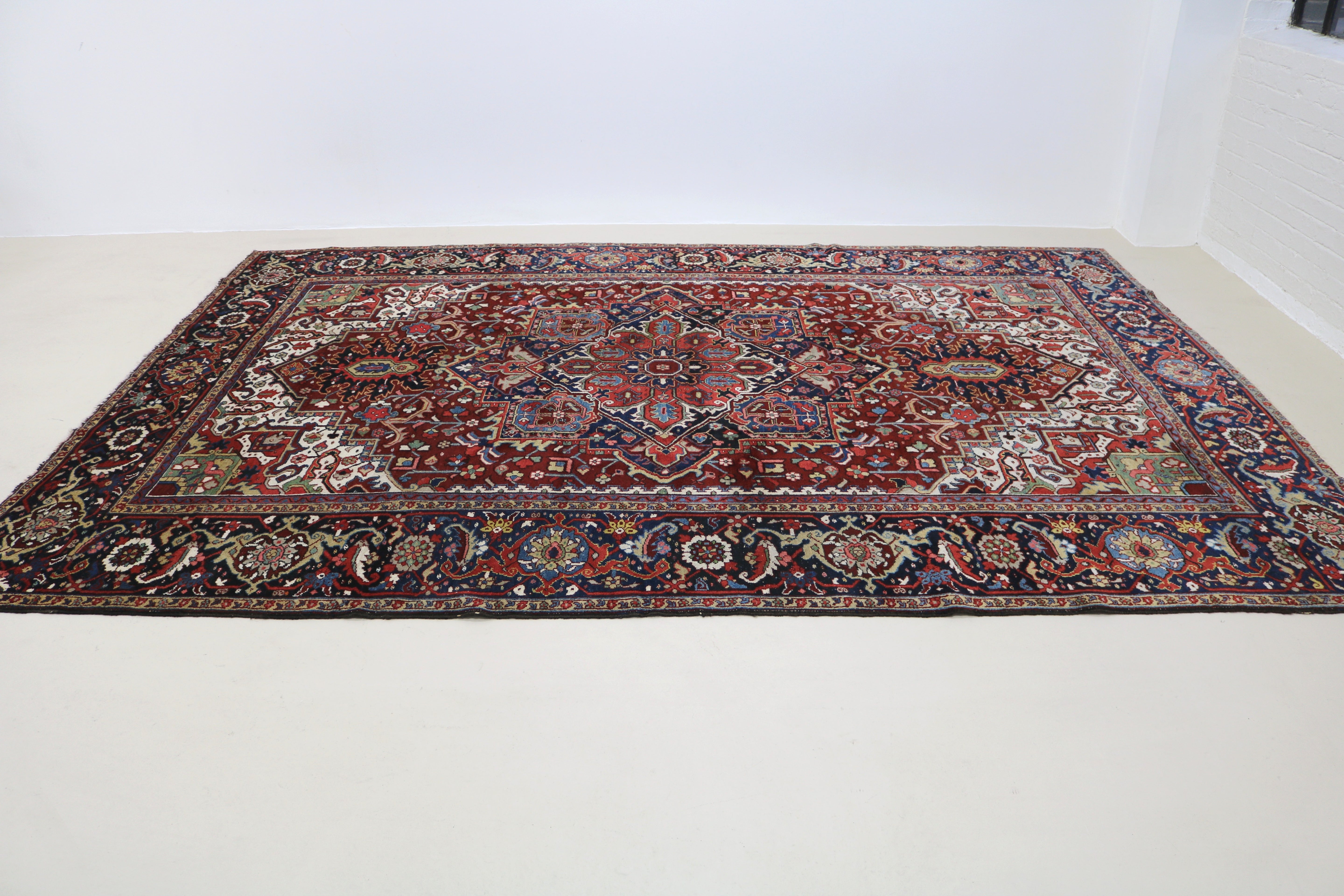 Perspective view of fine antique Persian Heriz carpet laid on floor