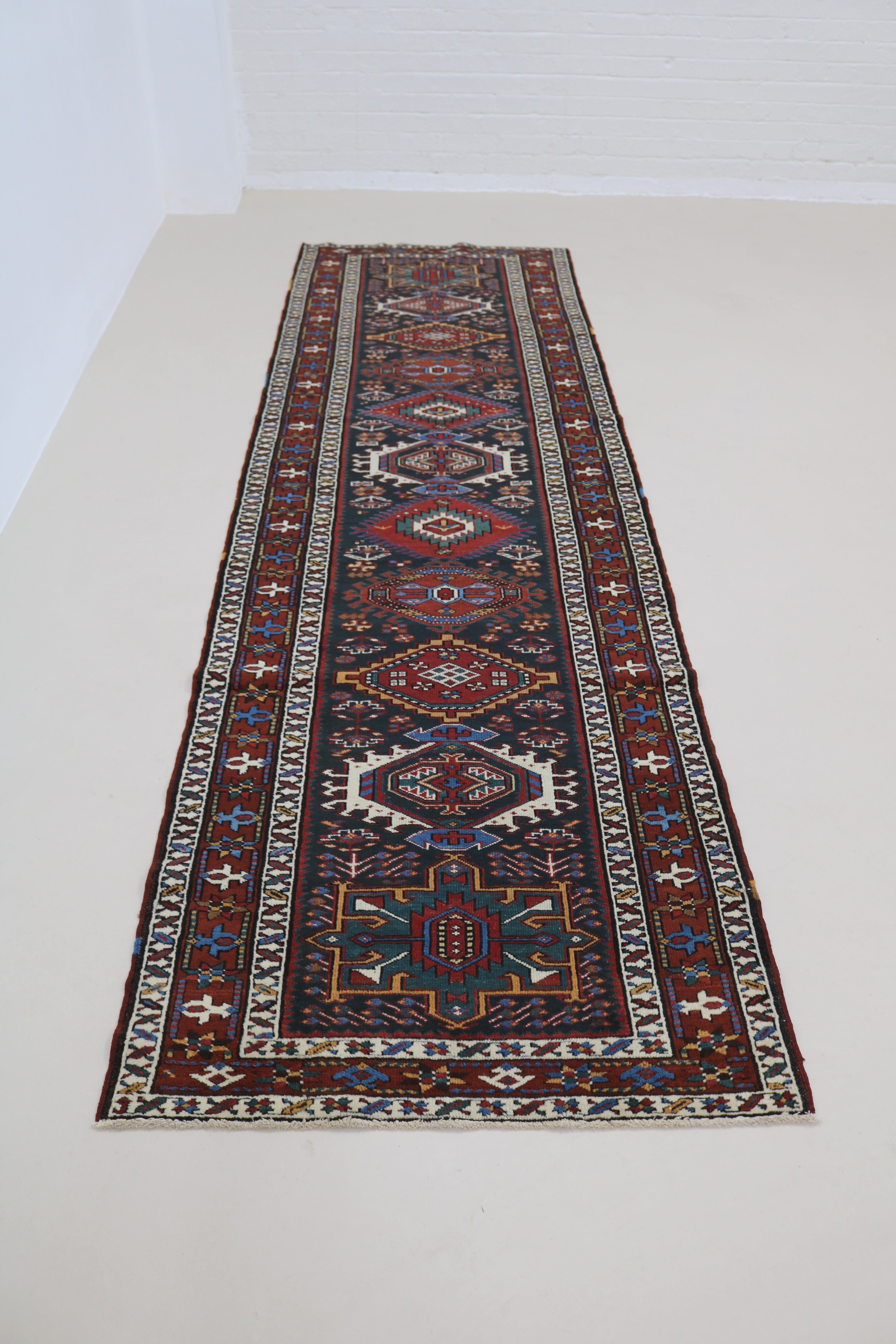Full view of antique Heriz runner with strong geometric field and traditional borders