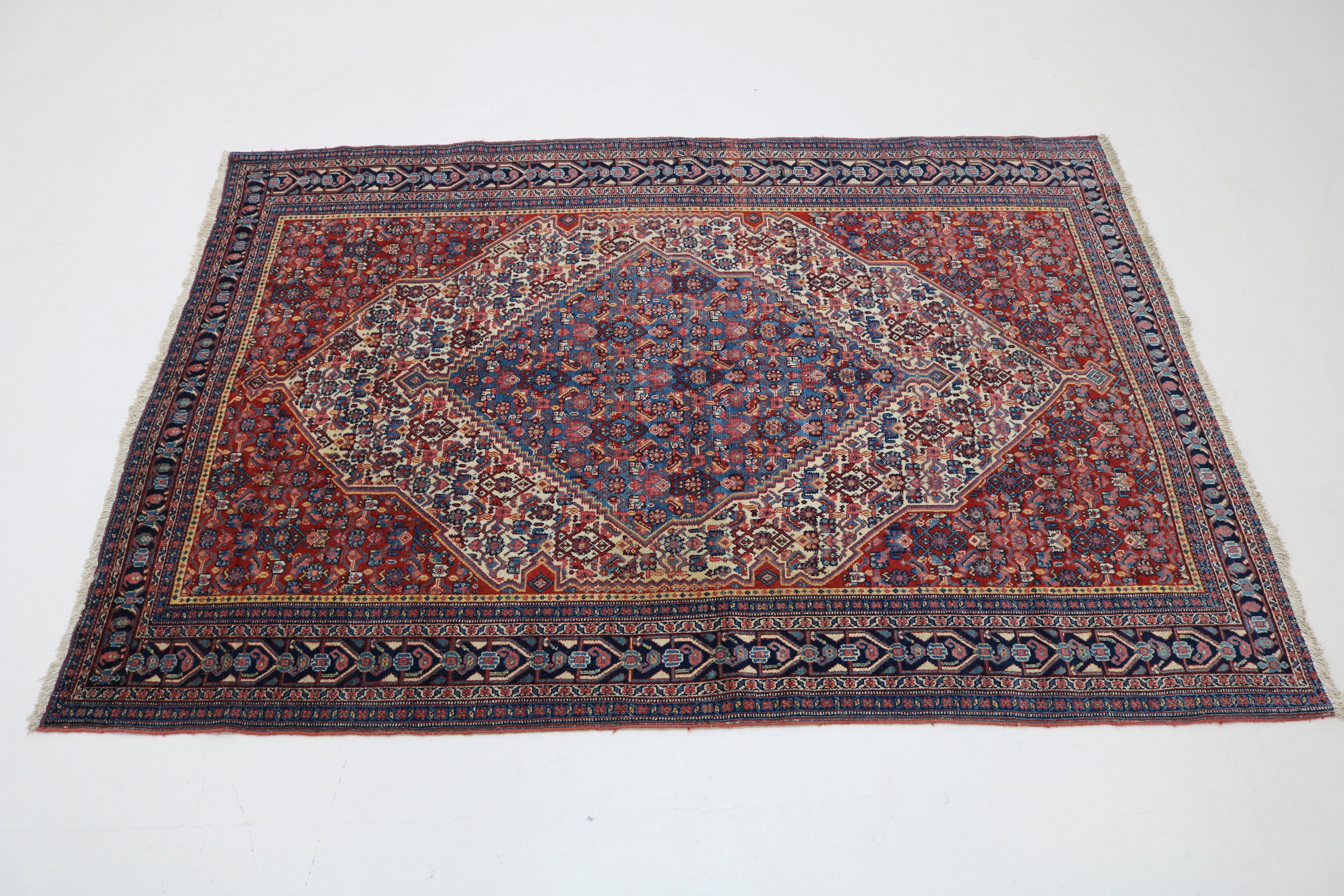 Perspective view of antique Persian Senneh rug laid on floor