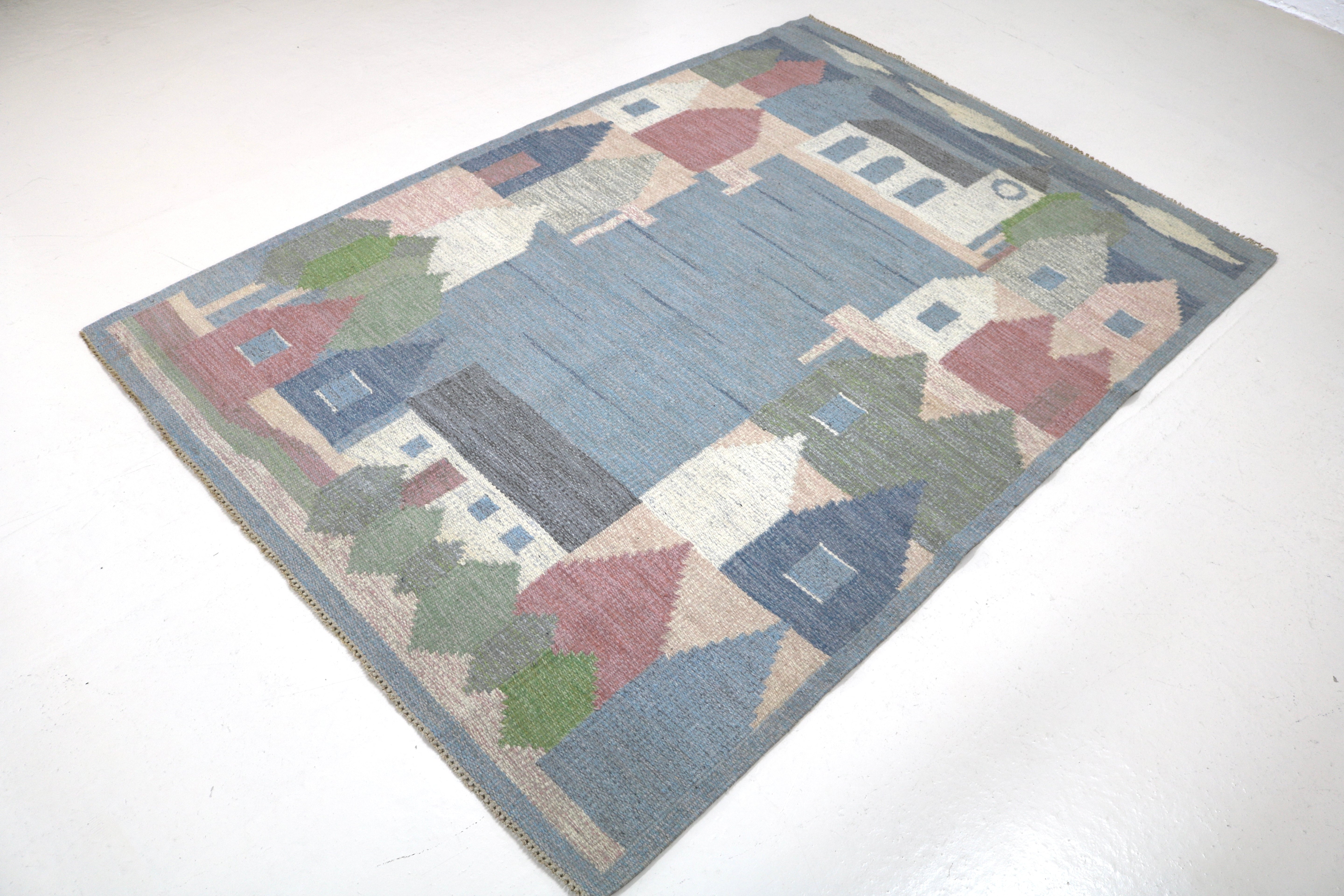 Authentic Swedish flatweave rug displaying colourful Scandinavian houses and trees.