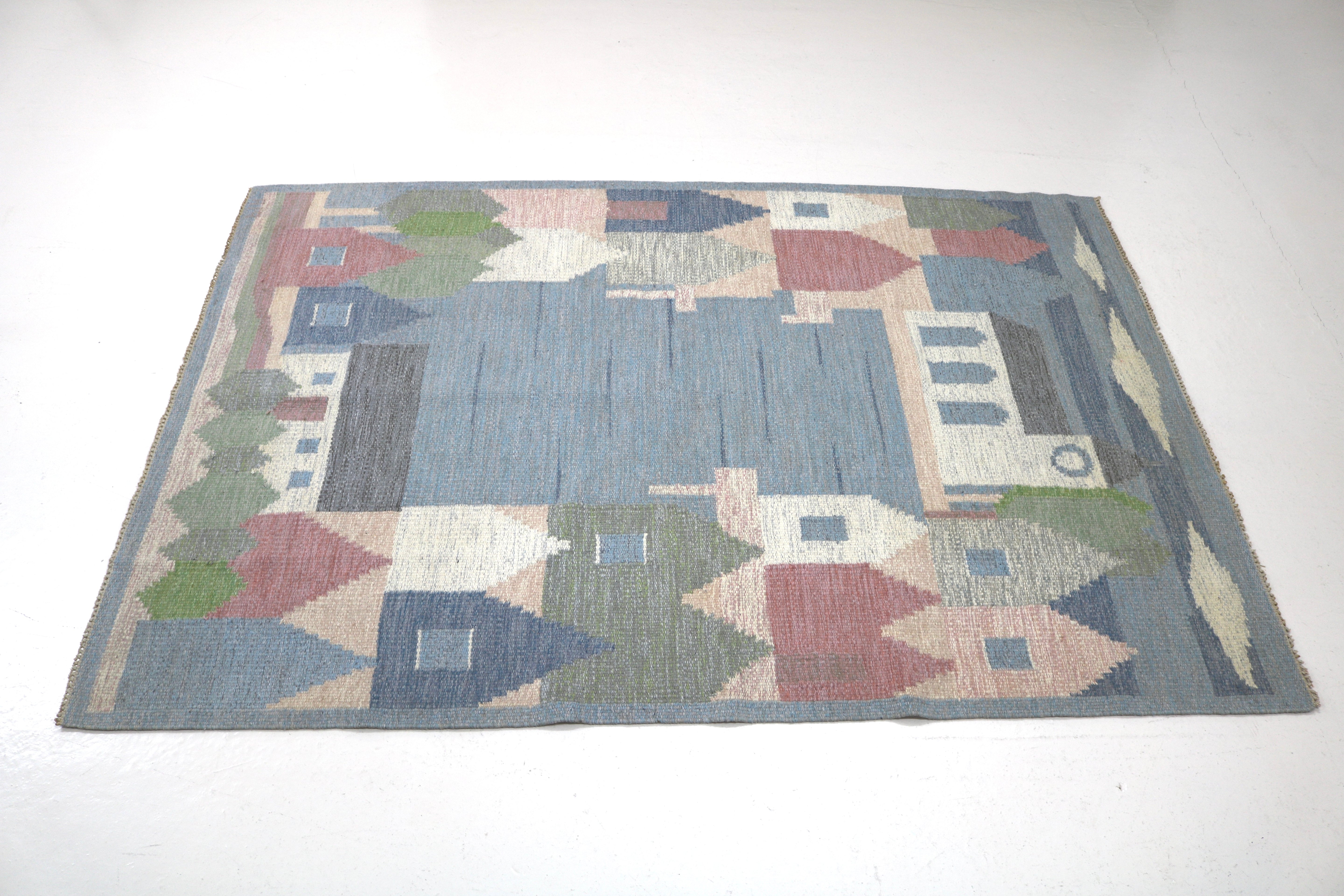 Angled view of a vintage Swedish kilim with landscape-inspired woven motifs.