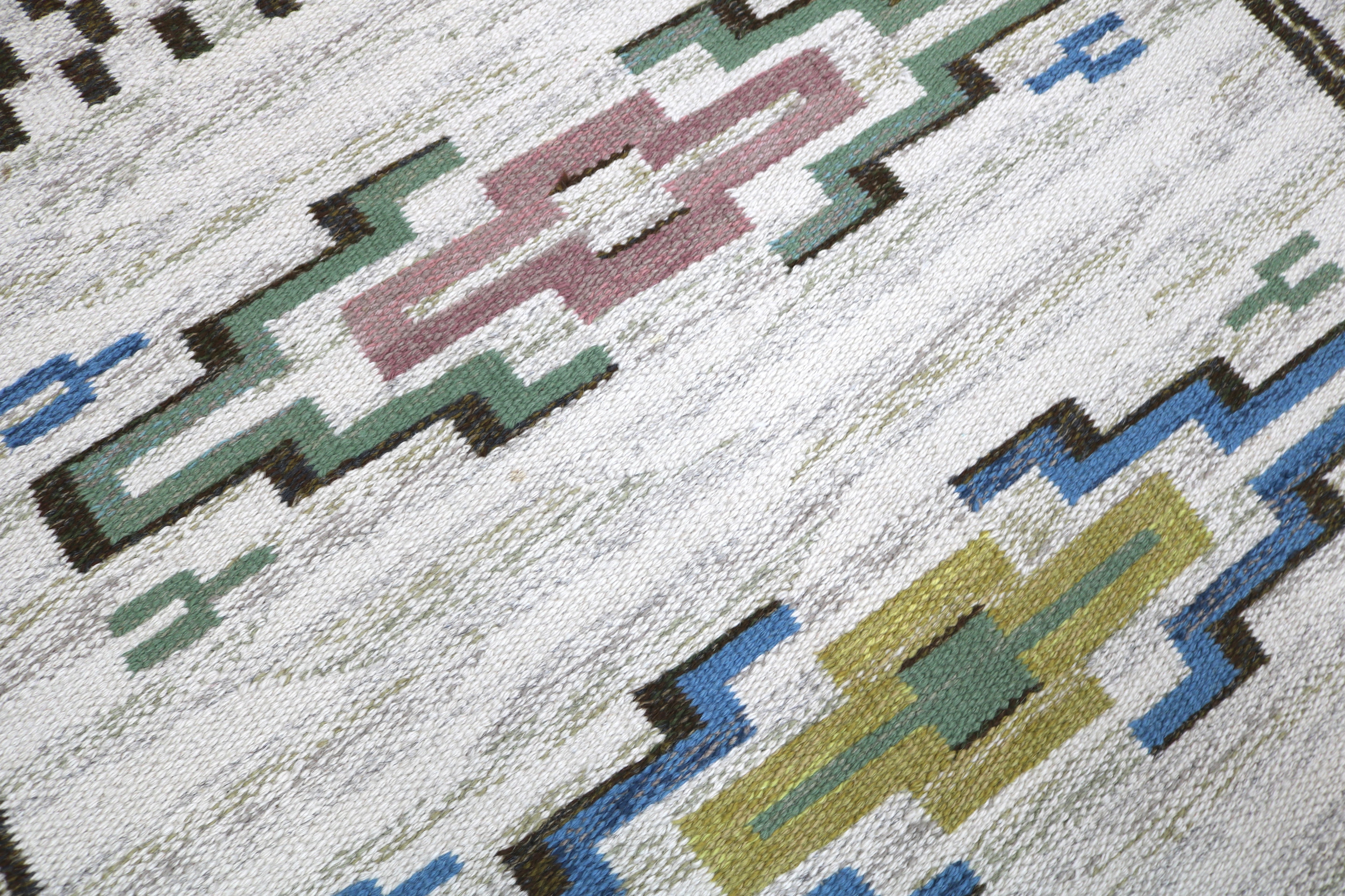 Corner detail of a handwoven Swedish wool rug with traditional geometric design.