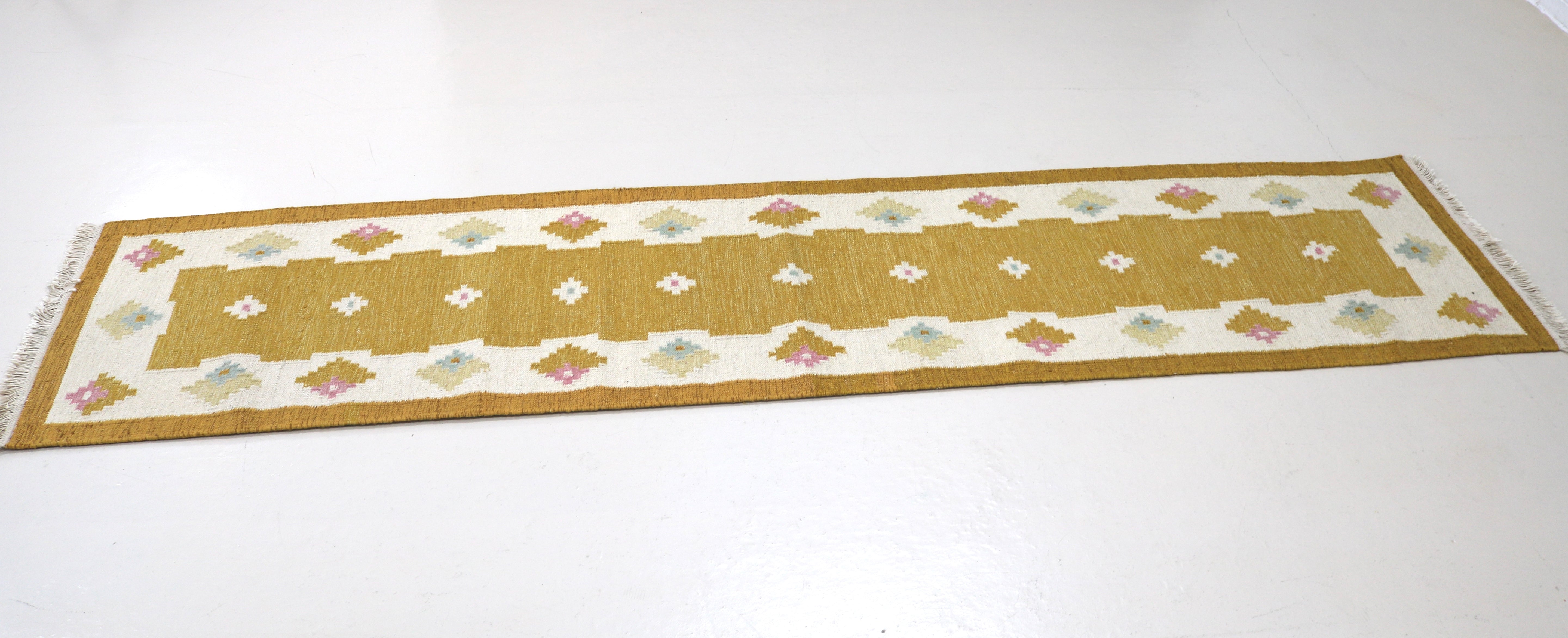 Angled view of a vintage Swedish flatweave runner with ivory border.
