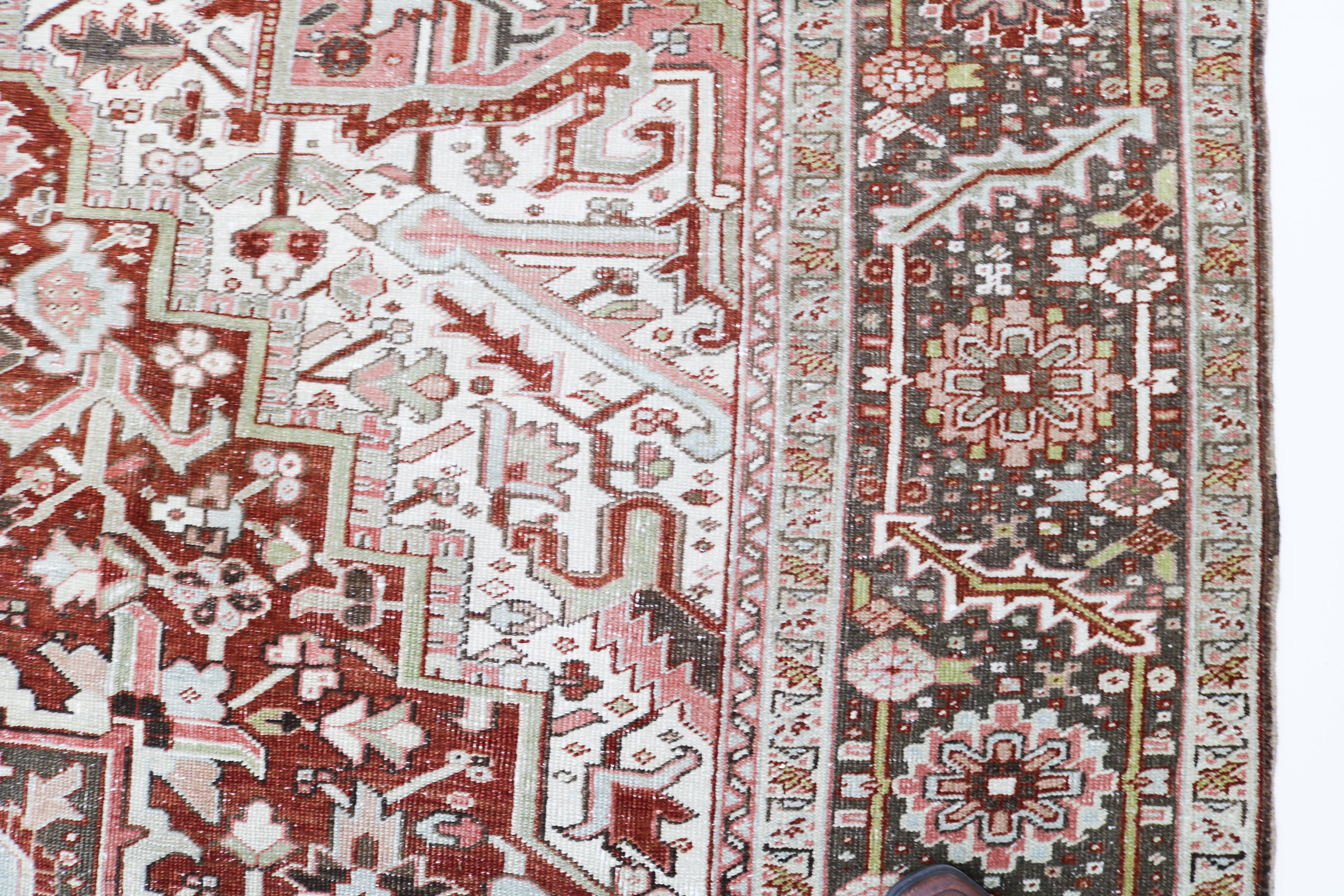 Close-up detail of antique Persian Heriz rug showing handwoven geometric motifs and natural wool colours
