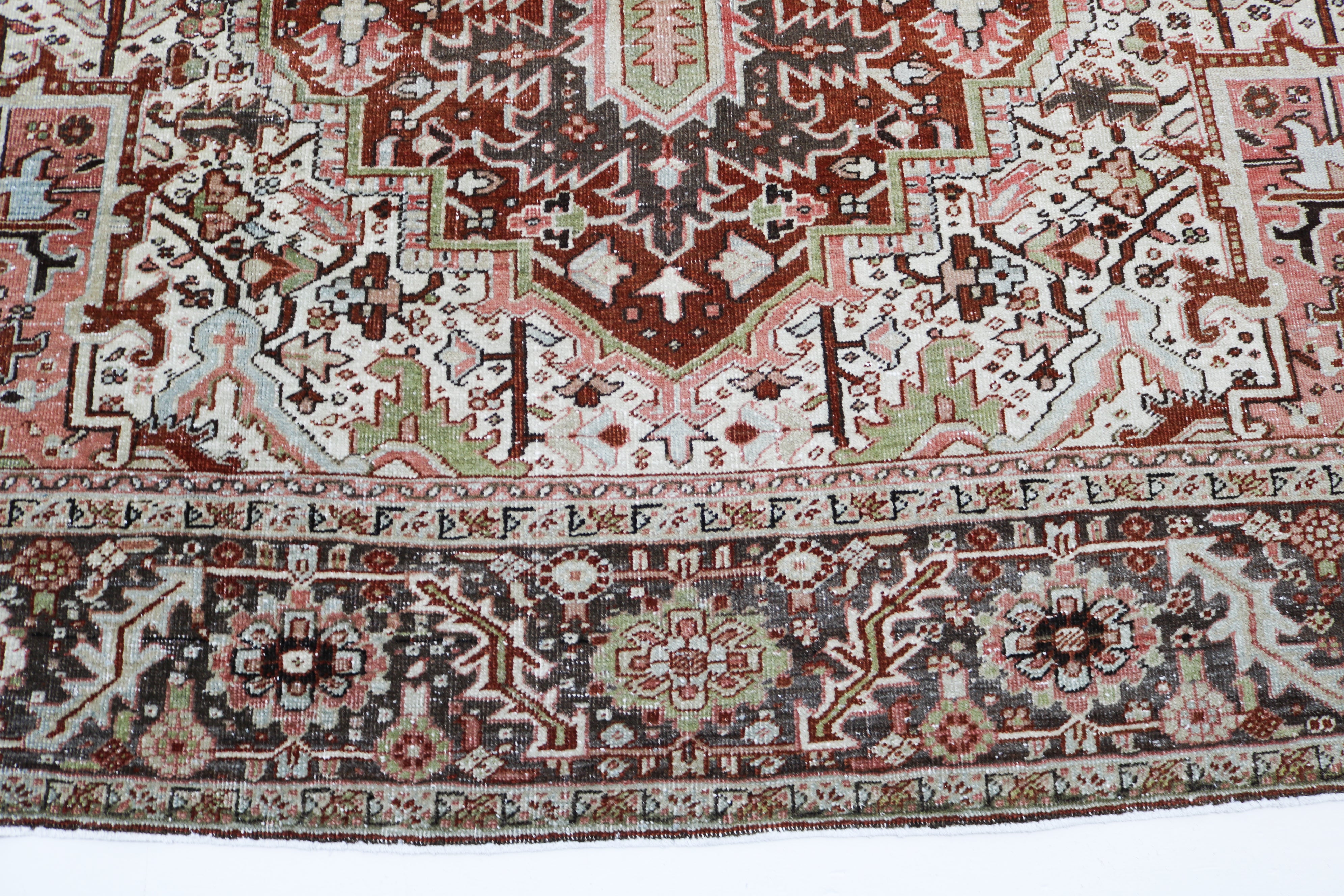 Close-up detail of antique Persian Heriz rug showing handwoven geometric motifs and natural wool colours