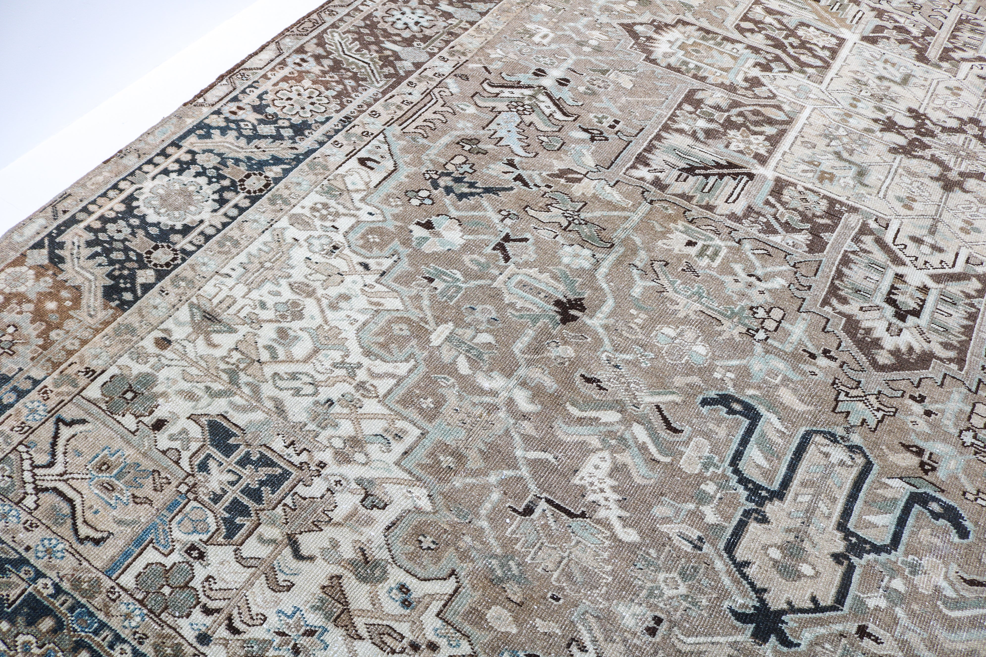 Close-up detail of antique Persian Heriz rug showing handwoven geometric motifs and naturally aged wool colours