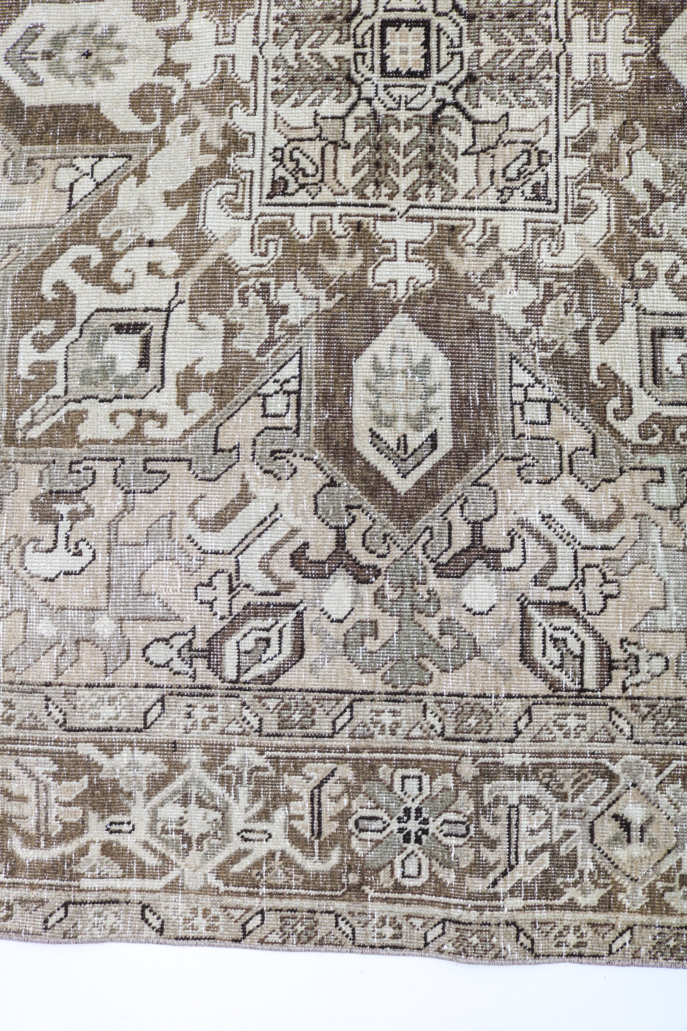 Vintage Persian carpet detail featuring traditional geometric motifs and soft ivory accents