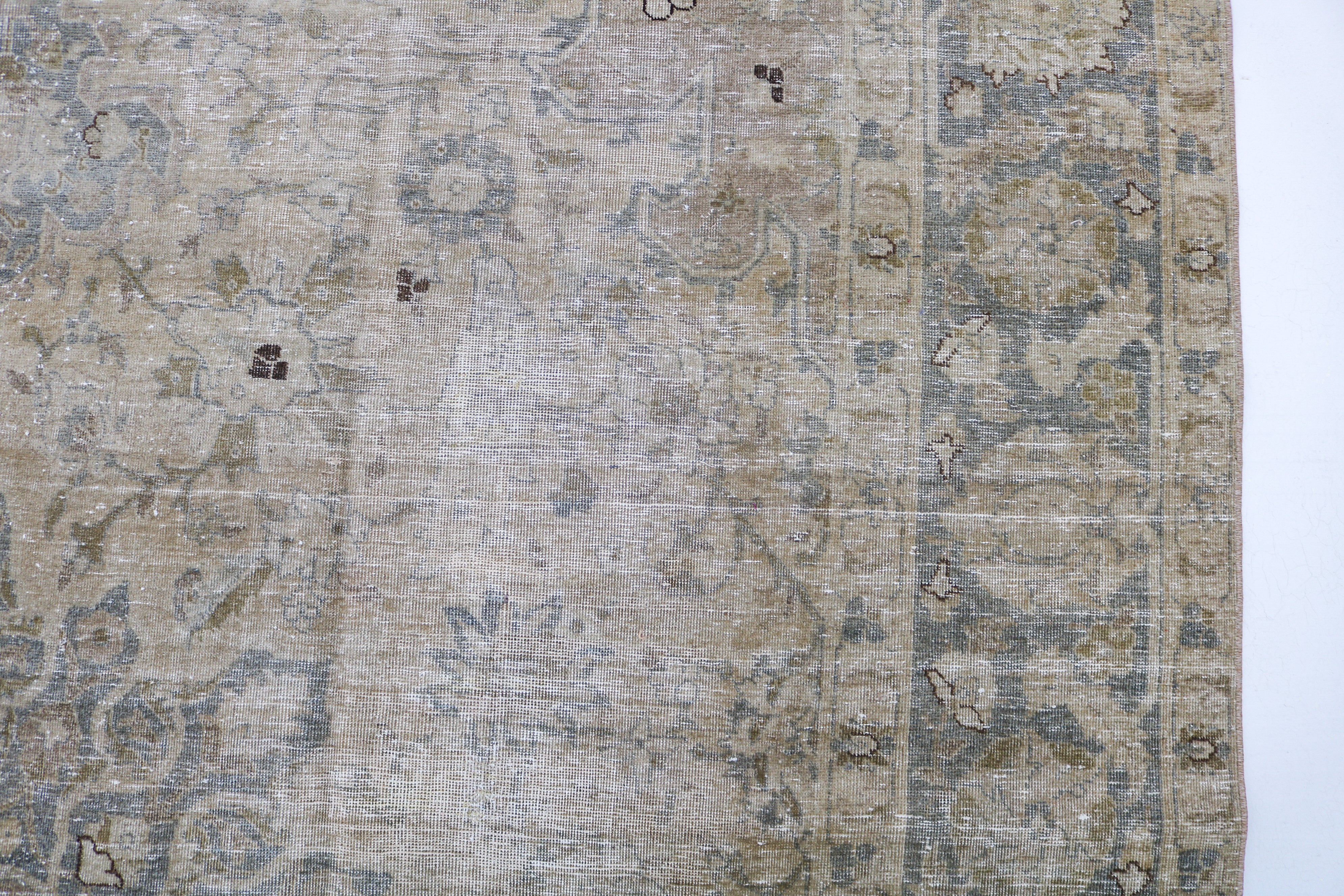Close-up of hand-knotted Persian Tabriz rug showing intricate border patterns and authentic aged patina