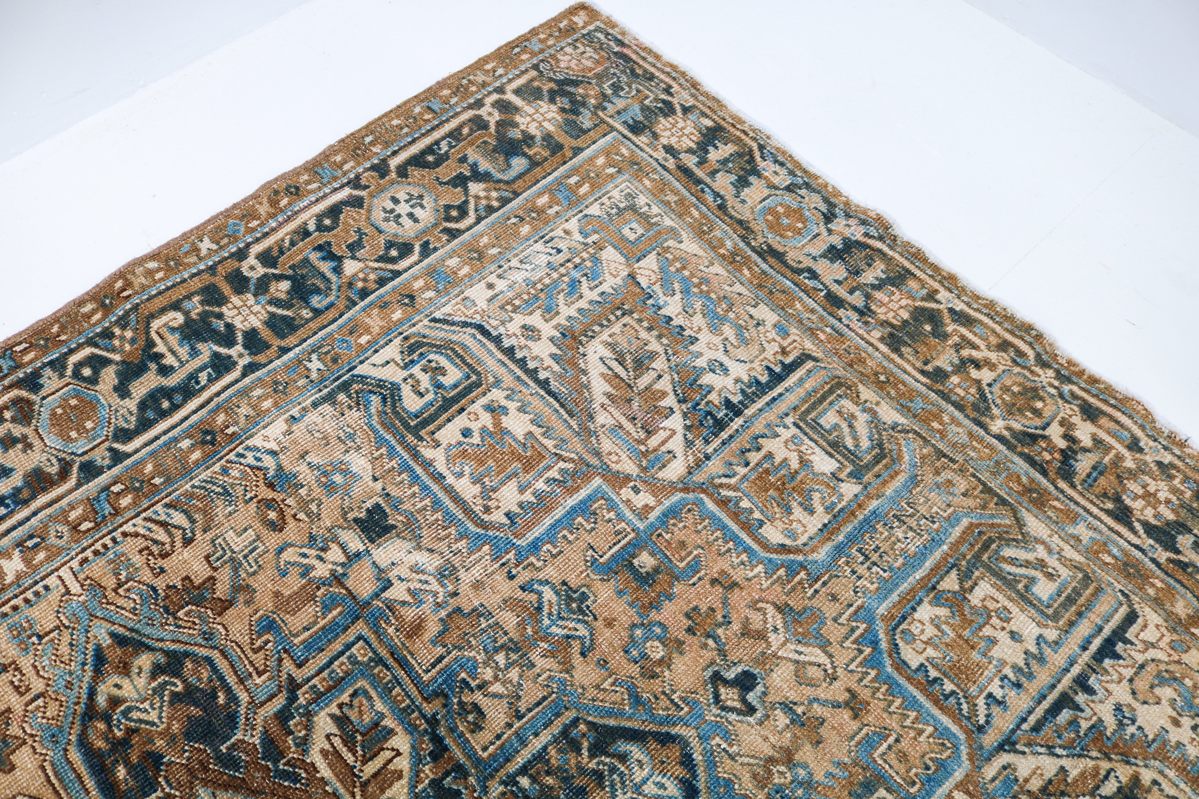 Close-up detail of antique Persian Heriz rug showing handwoven geometric motifs and aged wool colours
