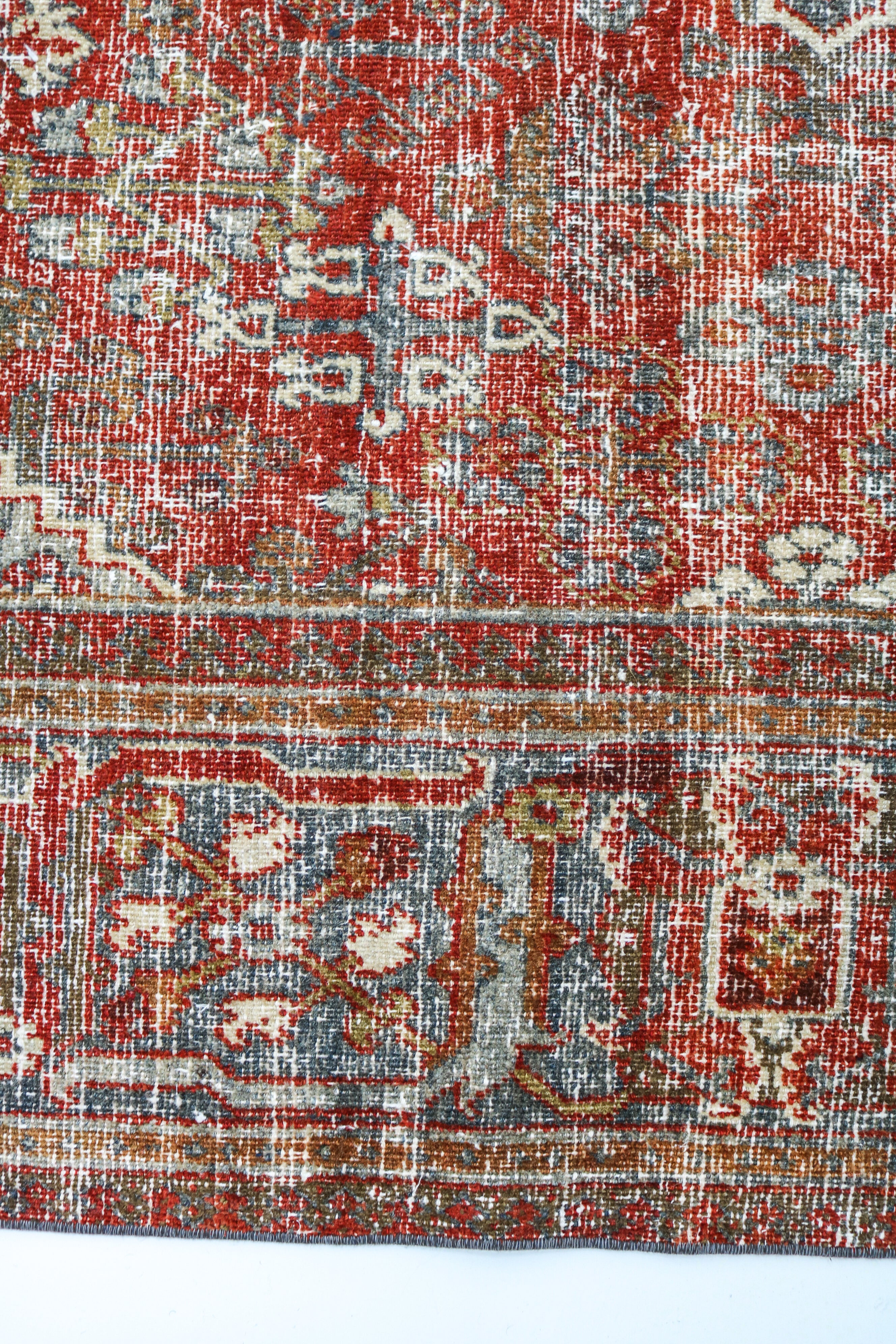 Antique Persian carpet close-up showing fine geometric weaving and subtle natural colour variation