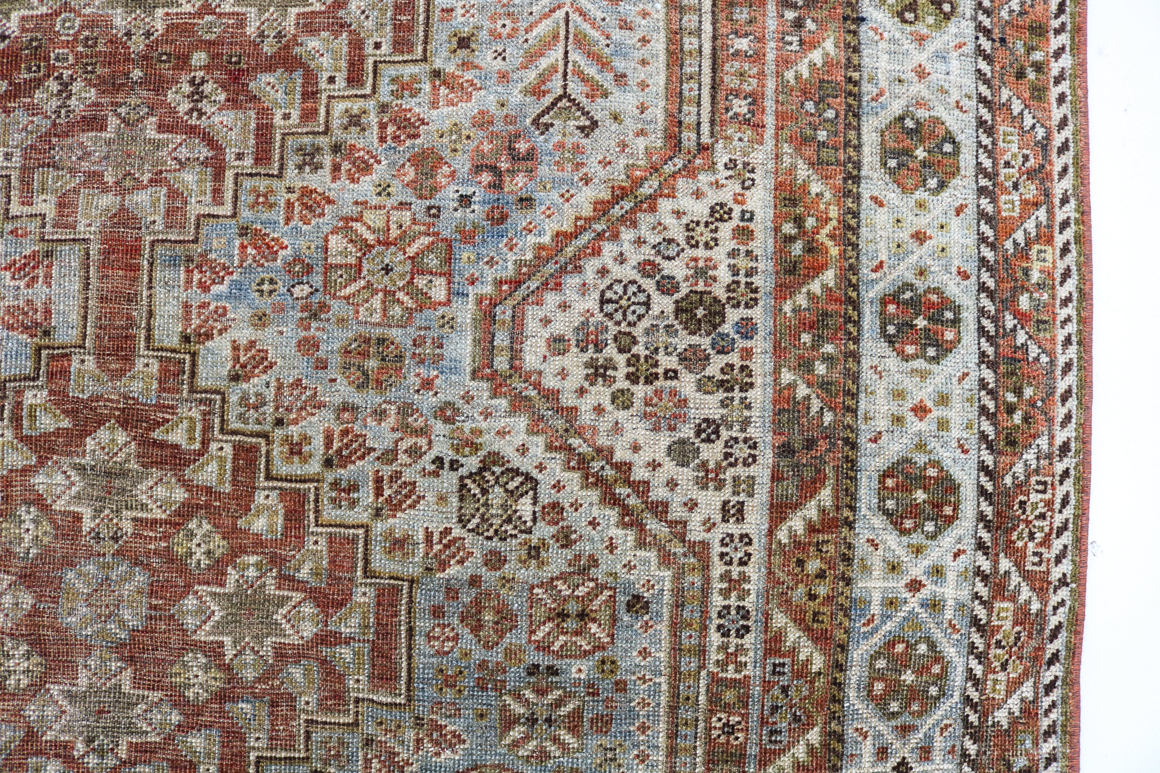 Close-up detail of antique Persian Qashqai rug showing handwoven tribal motifs and aged wool colours