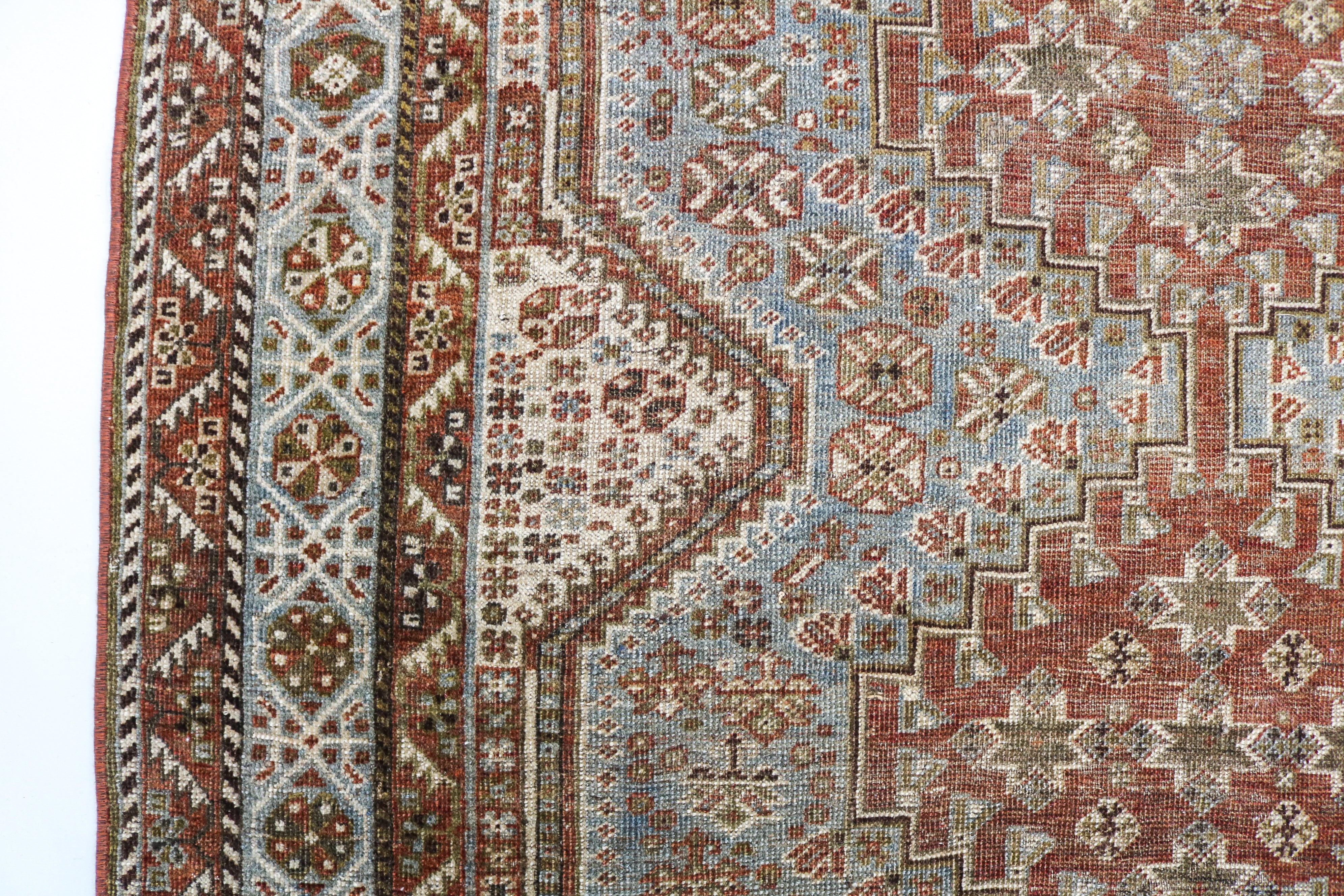 Detail of antique Persian Qashqai rug with geometric tribal motifs and naturally faded terracotta tones