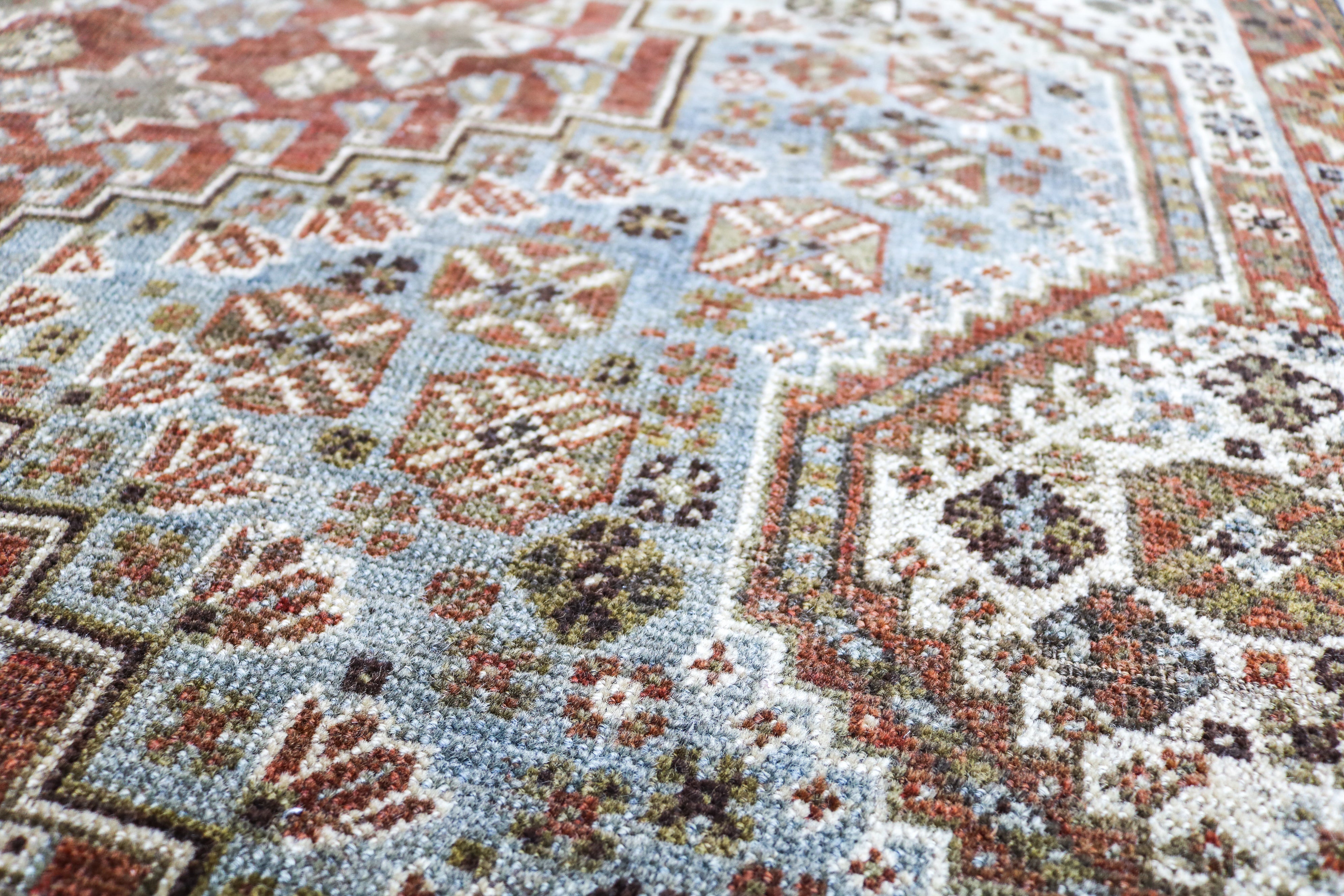 Detail of antique Persian Qashqai rug with geometric tribal motifs and naturally faded terracotta tones