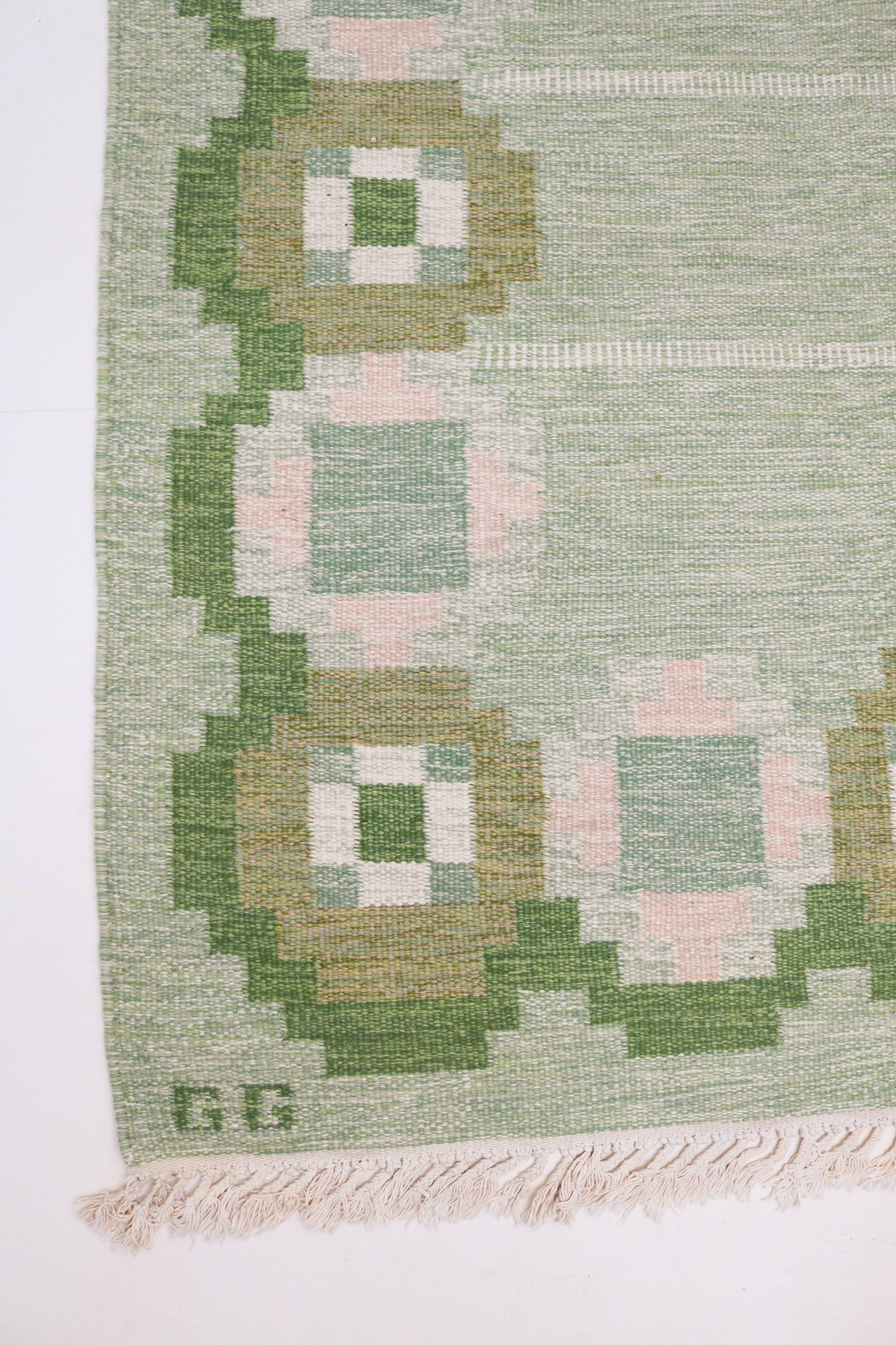 Close-up of vintage Swedish kilim rug with green and pale pink geometric design