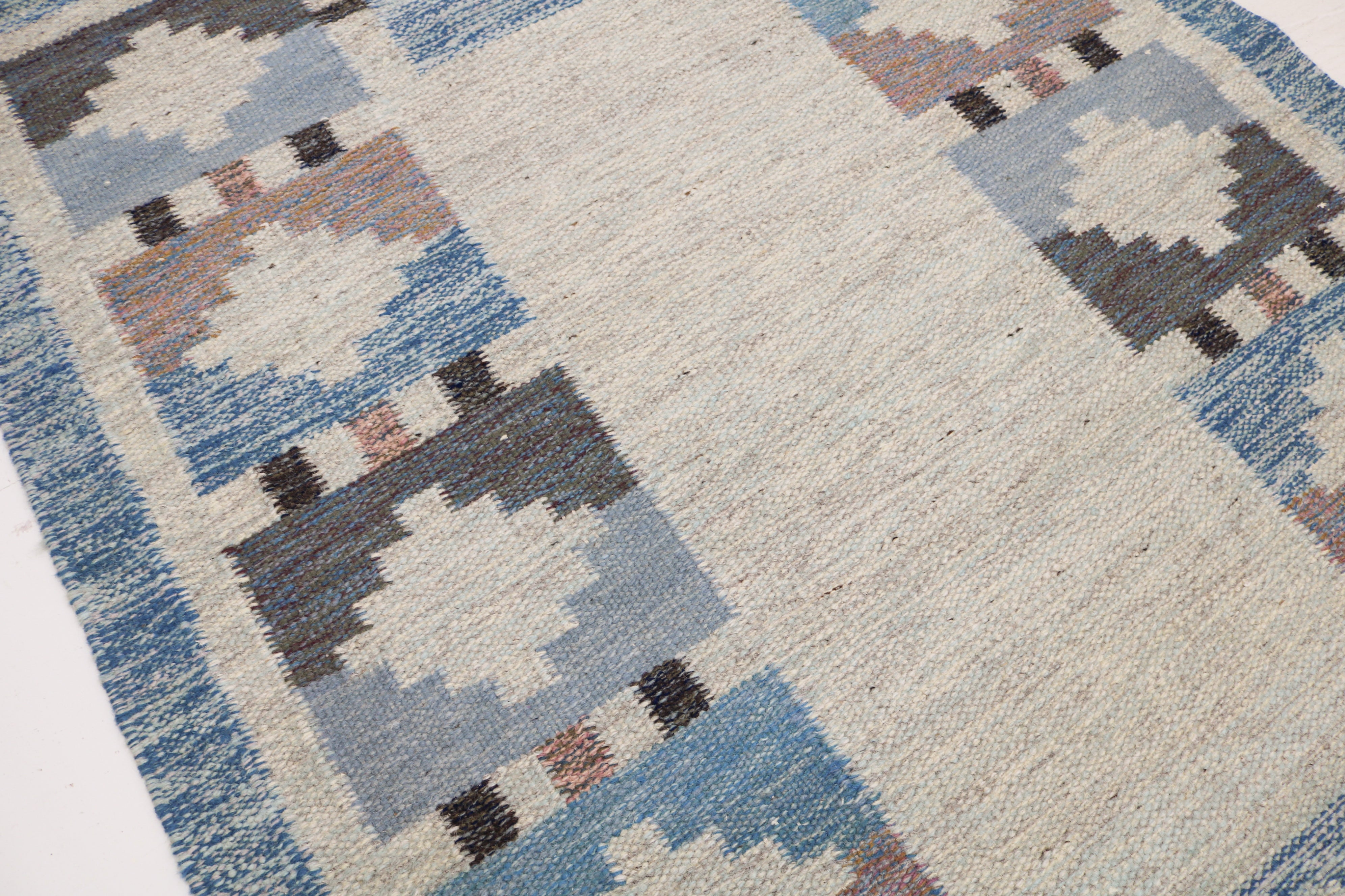 Detail of vintage Swedish kilim rug in blue, ivory and dusty pink