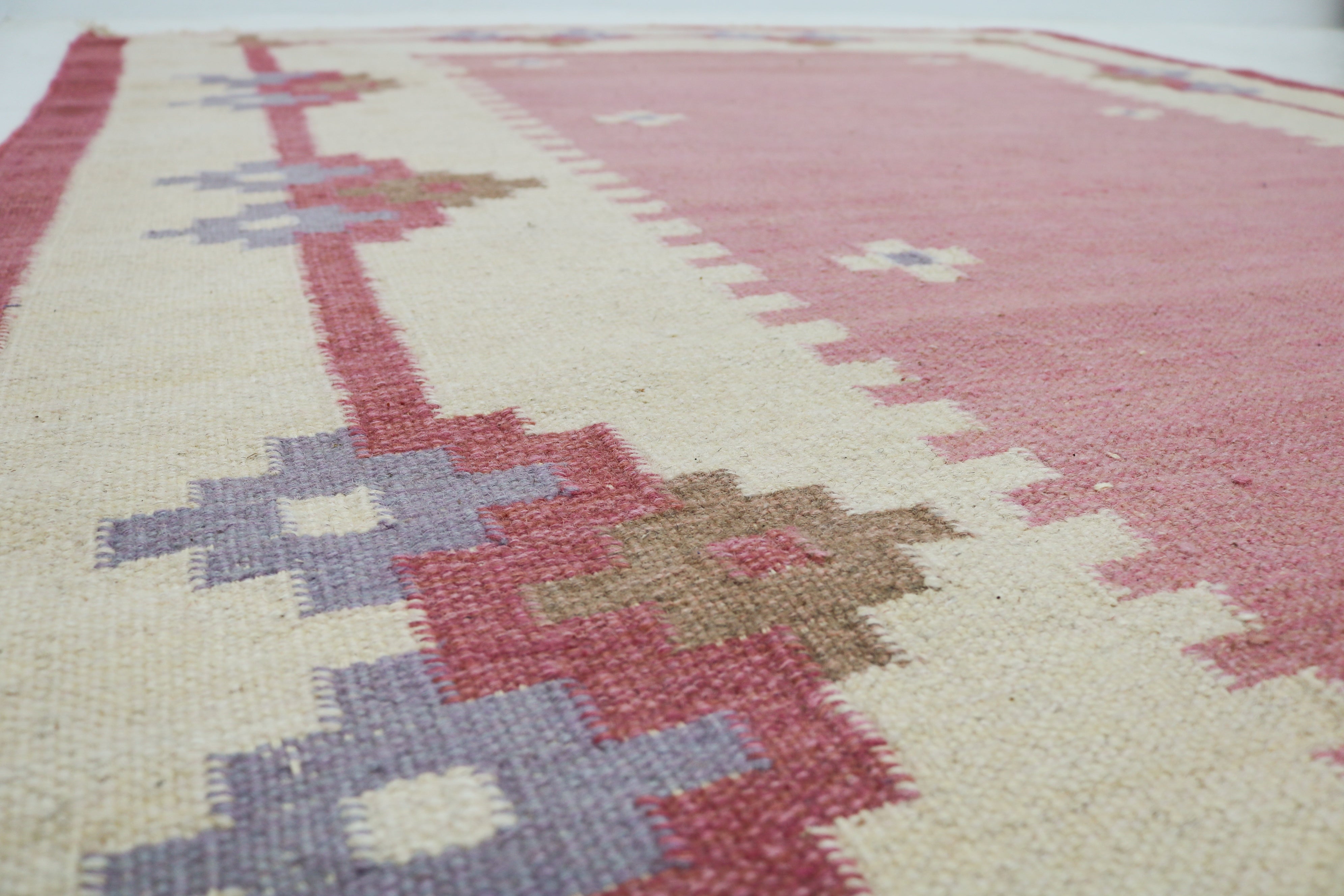 Detail of vintage Swedish kilim rug in dusty pink, ivory and muted lavender