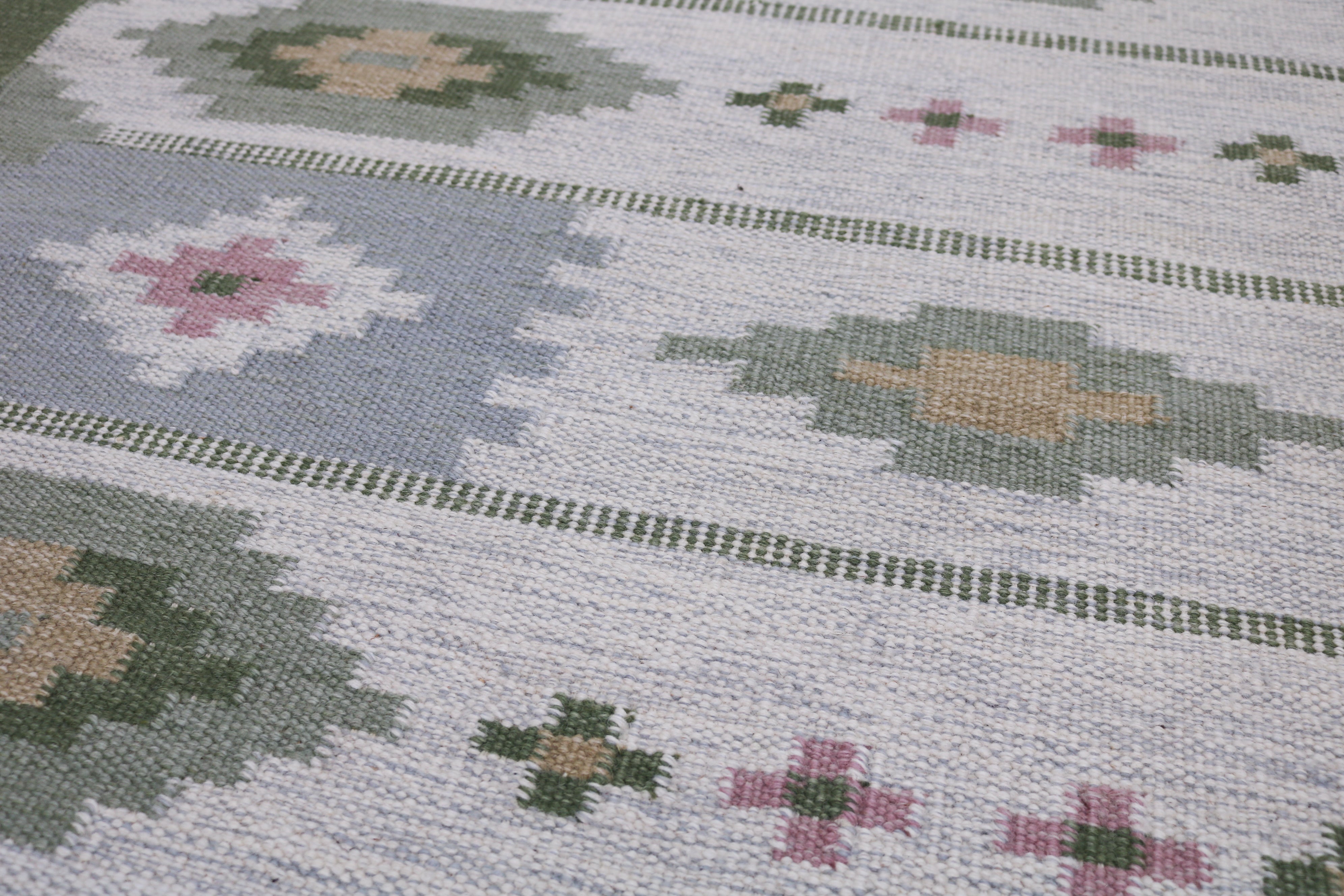 Close-up of green ivory and grey geometric pattern on vintage Swedish wool Kilim rug